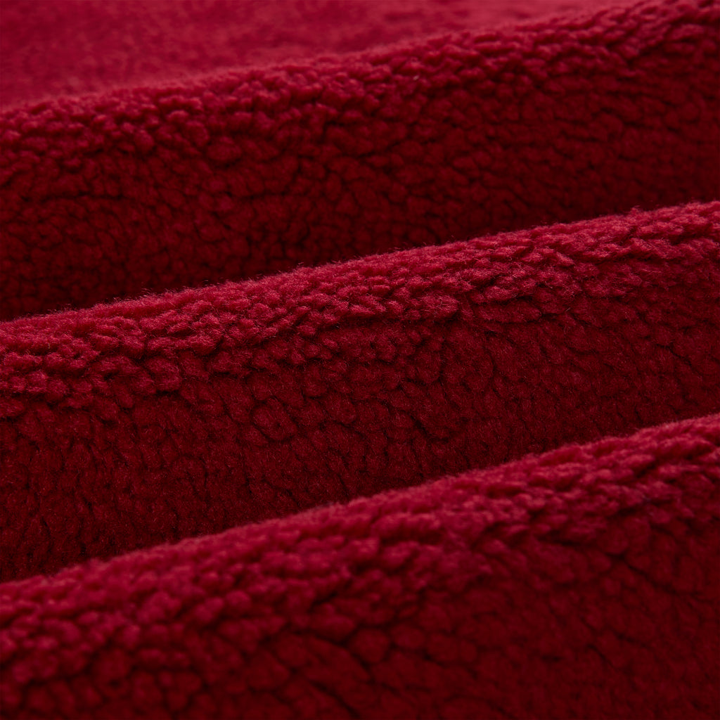 Close-up of soft, textured red sherpa fleece fabric, folded in waves.
