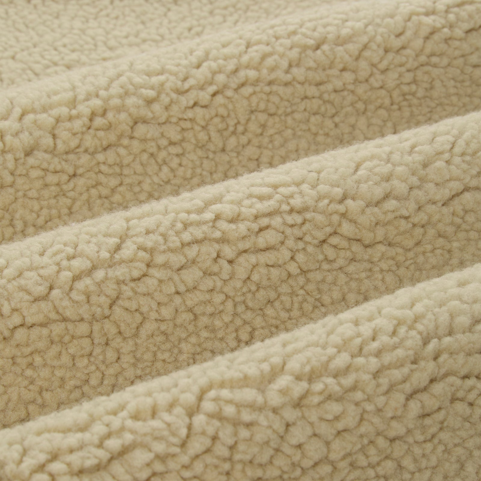 Close-up of soft, cream-colored sherpa fleece fabric with visible texture and folds.