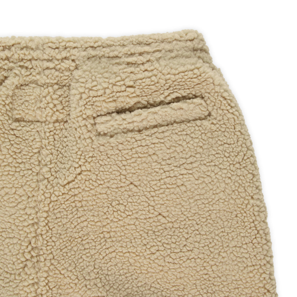 Close-up of a beige teddy sherpa fleece pant with an elasticized waistband and pocket.