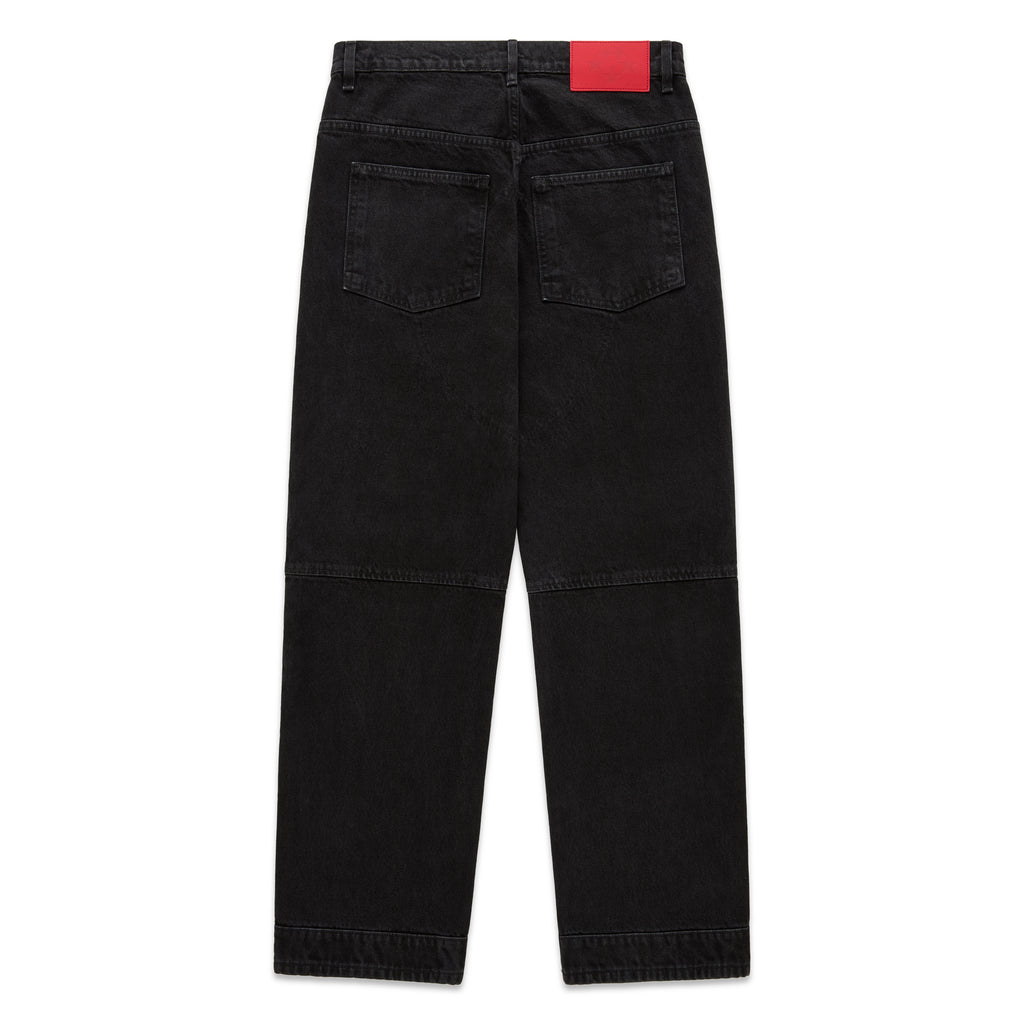 Faded black denim jeans with paneled knees, back pockets, and a red branded leather patch.