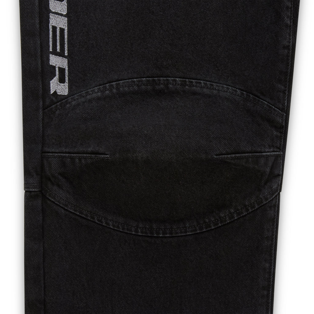 Faded black denim pant with "SP5DER" logo, paneled knee, and distressed details.