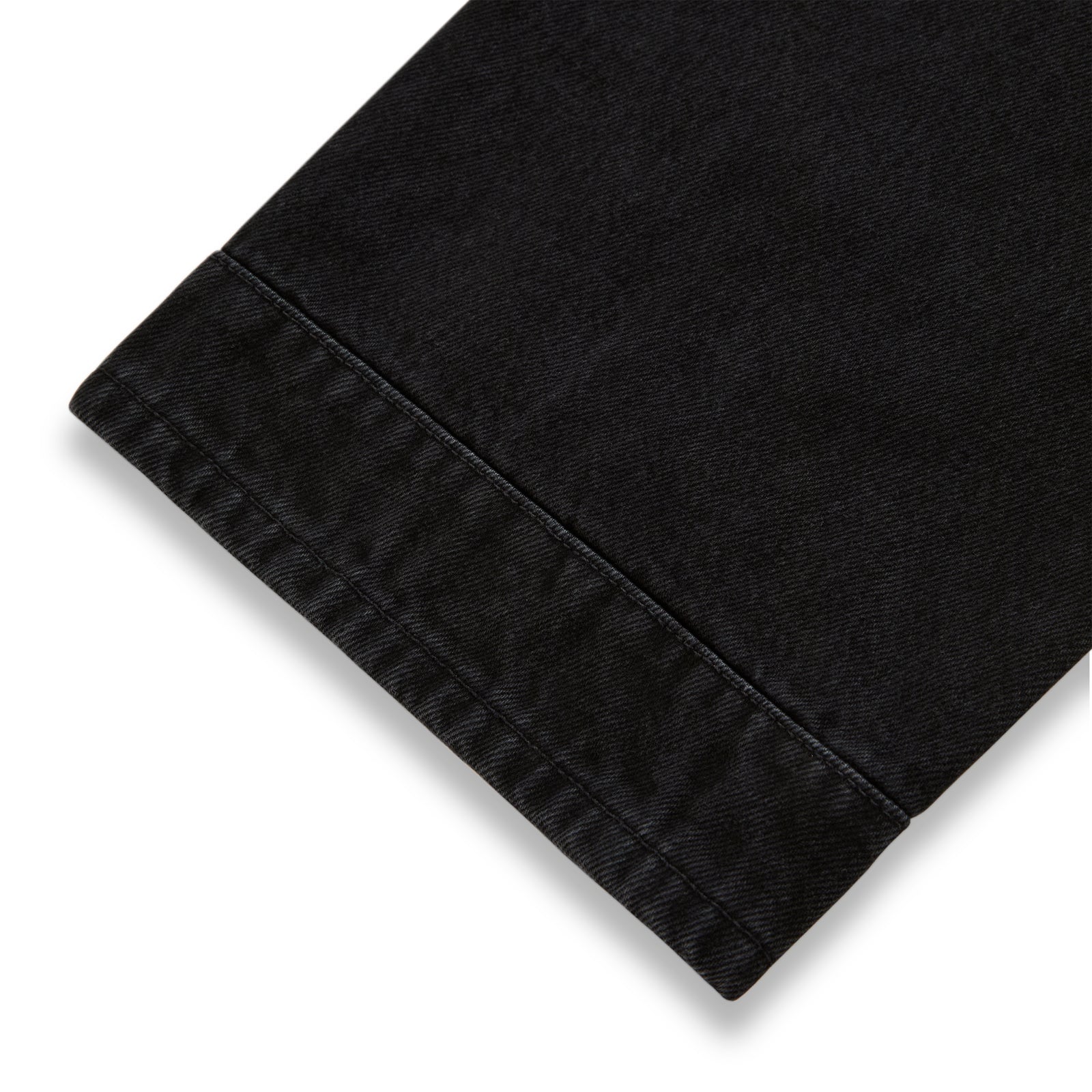 Close-up of black denim pant hem with distressed detailing.
