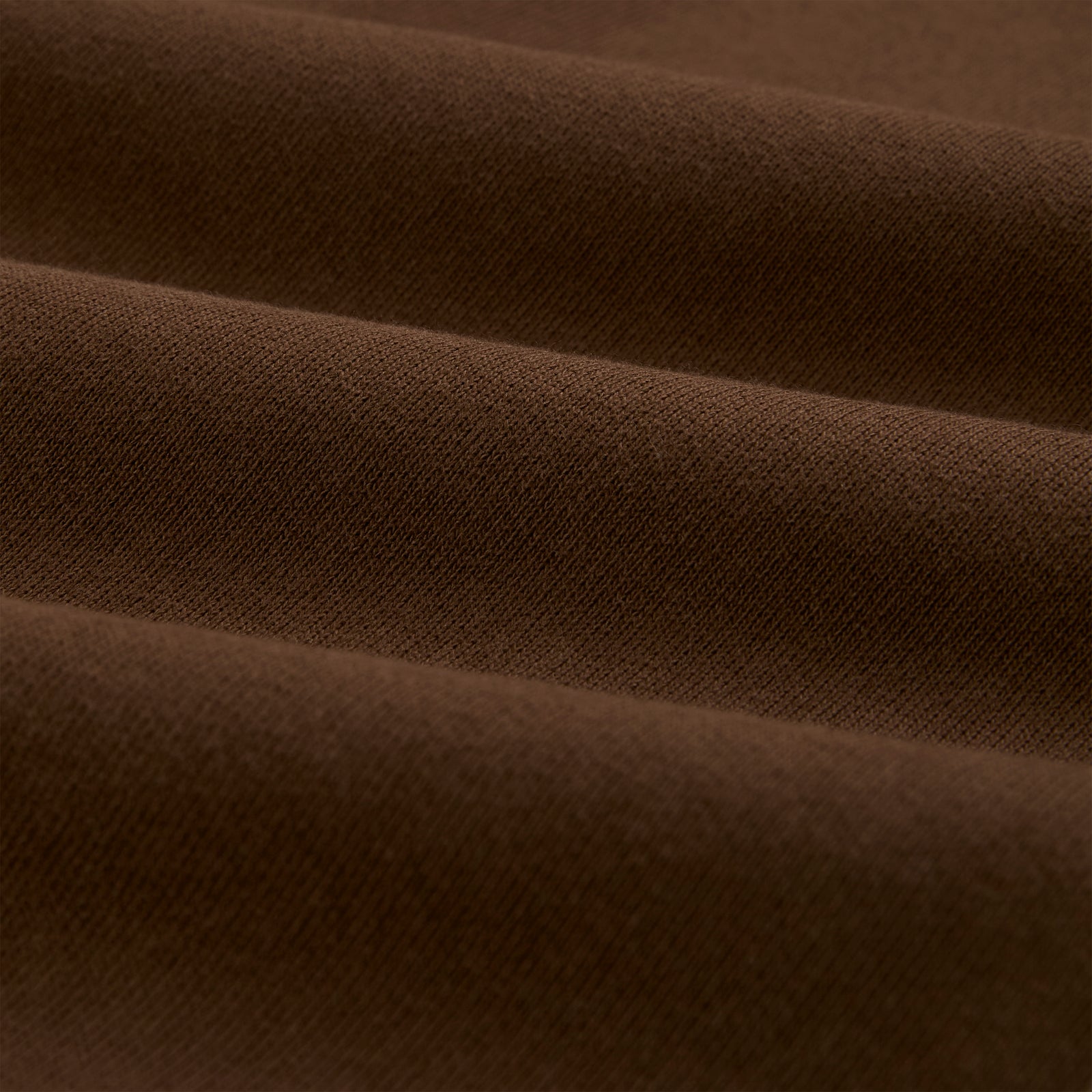 Close-up of brown 13oz cotton fleece fabric, showing its soft texture and folds.
