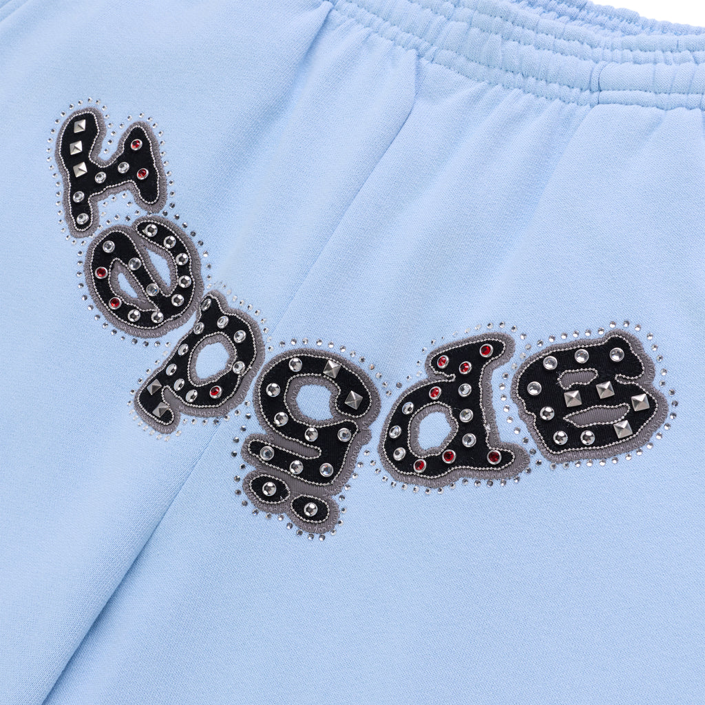 Light blue cotton fleece sweatpants with "Regalabs" logo appliqué embellished with mixed metal studs and red dome rivets.