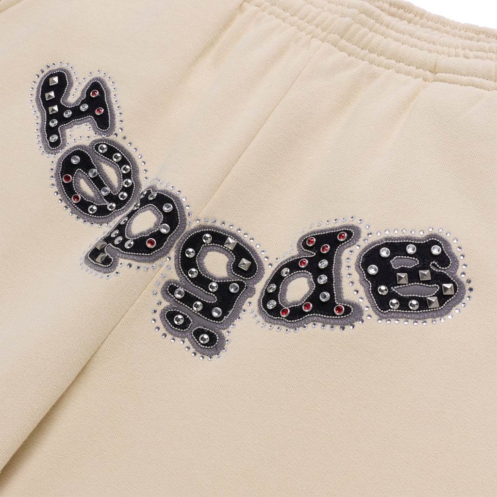 Beige cotton fleece sweatpants with "OG LOGO" appliqué embellished with mixed metal studs and red stones.