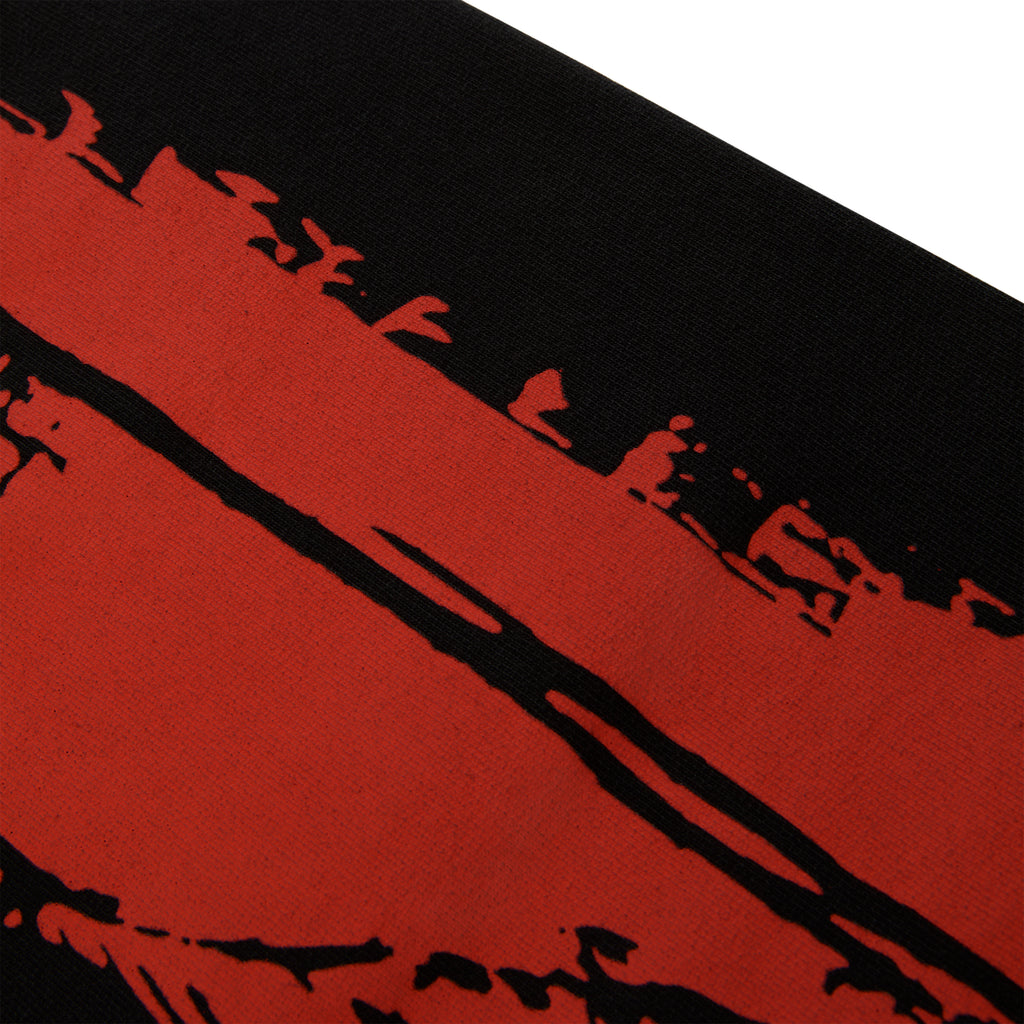 Close-up of black 13oz cotton fleece sweatpant with red painted moto design.