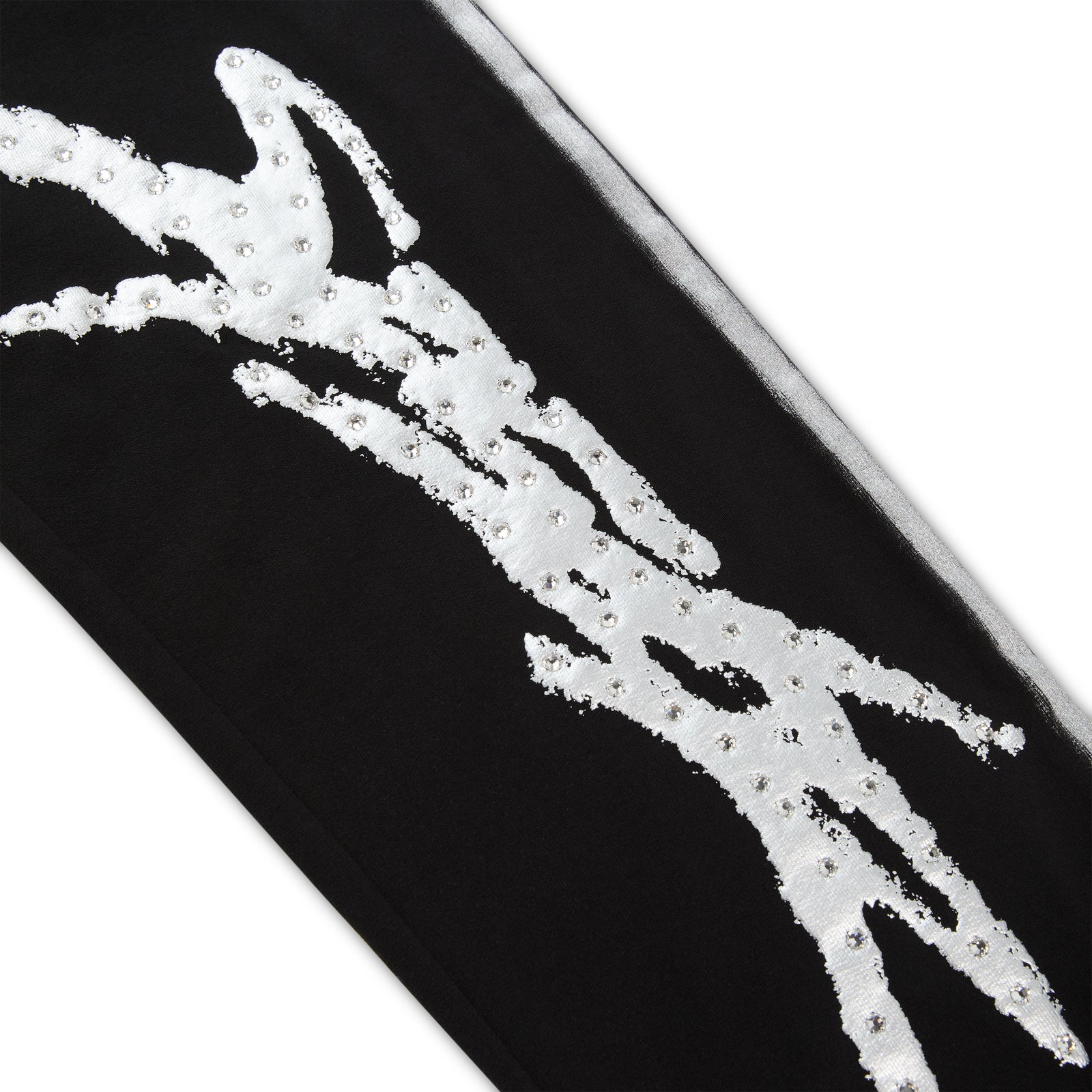 Black cotton fleece sweatpant leg with silver "SP5DER" logo, rhinestone accents, and sprayed-effect side stripe.