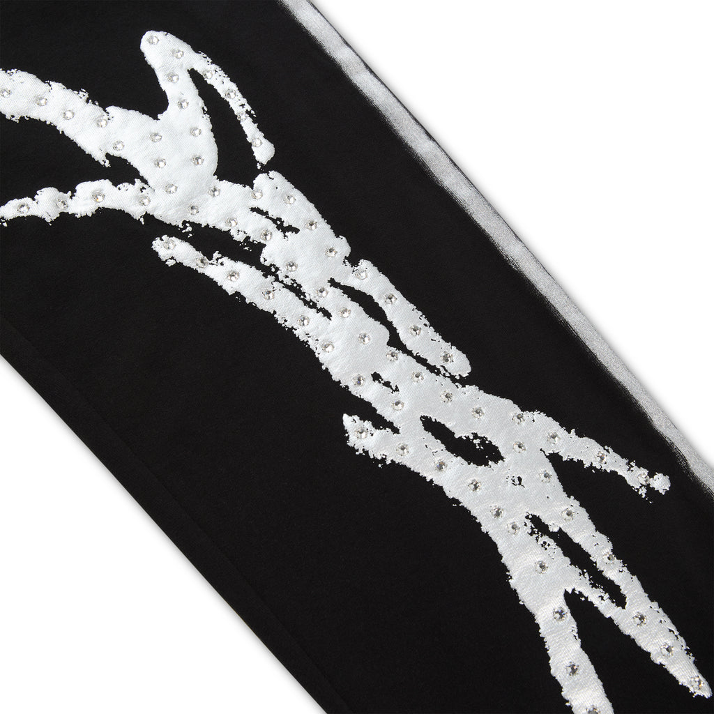 Black cotton fleece sweatpant leg with silver "SP5DER" logo, rhinestone accents, and sprayed-effect side stripe.
