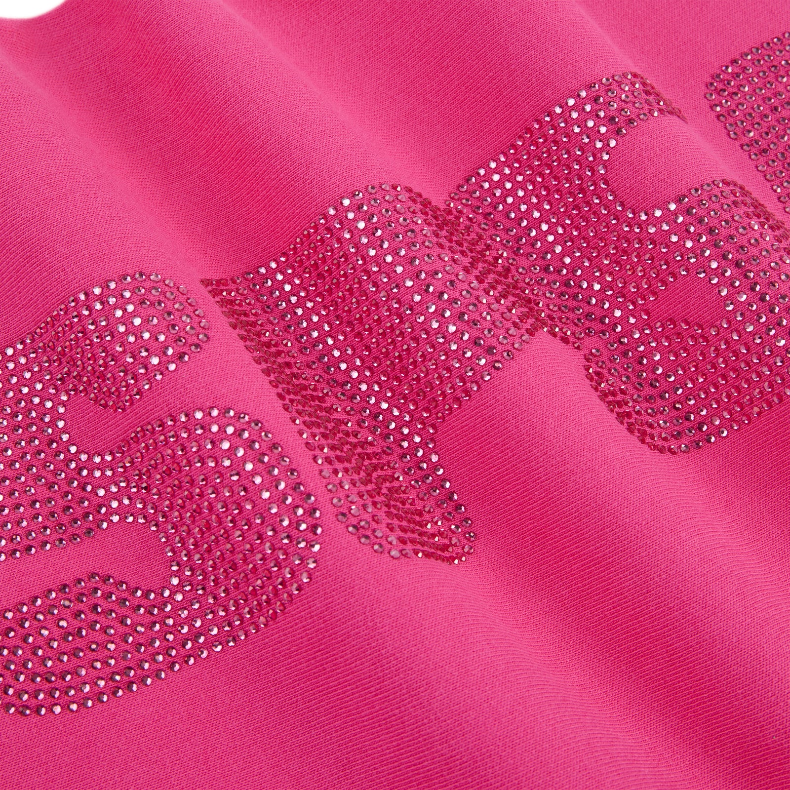 Close-up of a vibrant pink cotton fleece sweatpant with sparkling rhinestone embellishment.