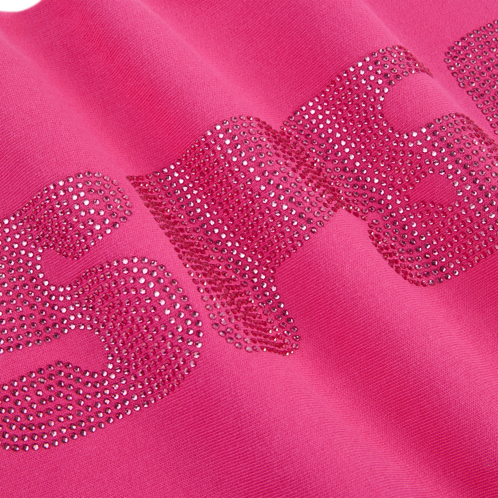Close-up of a vibrant pink cotton fleece sweatpant with sparkling rhinestone embellishment.