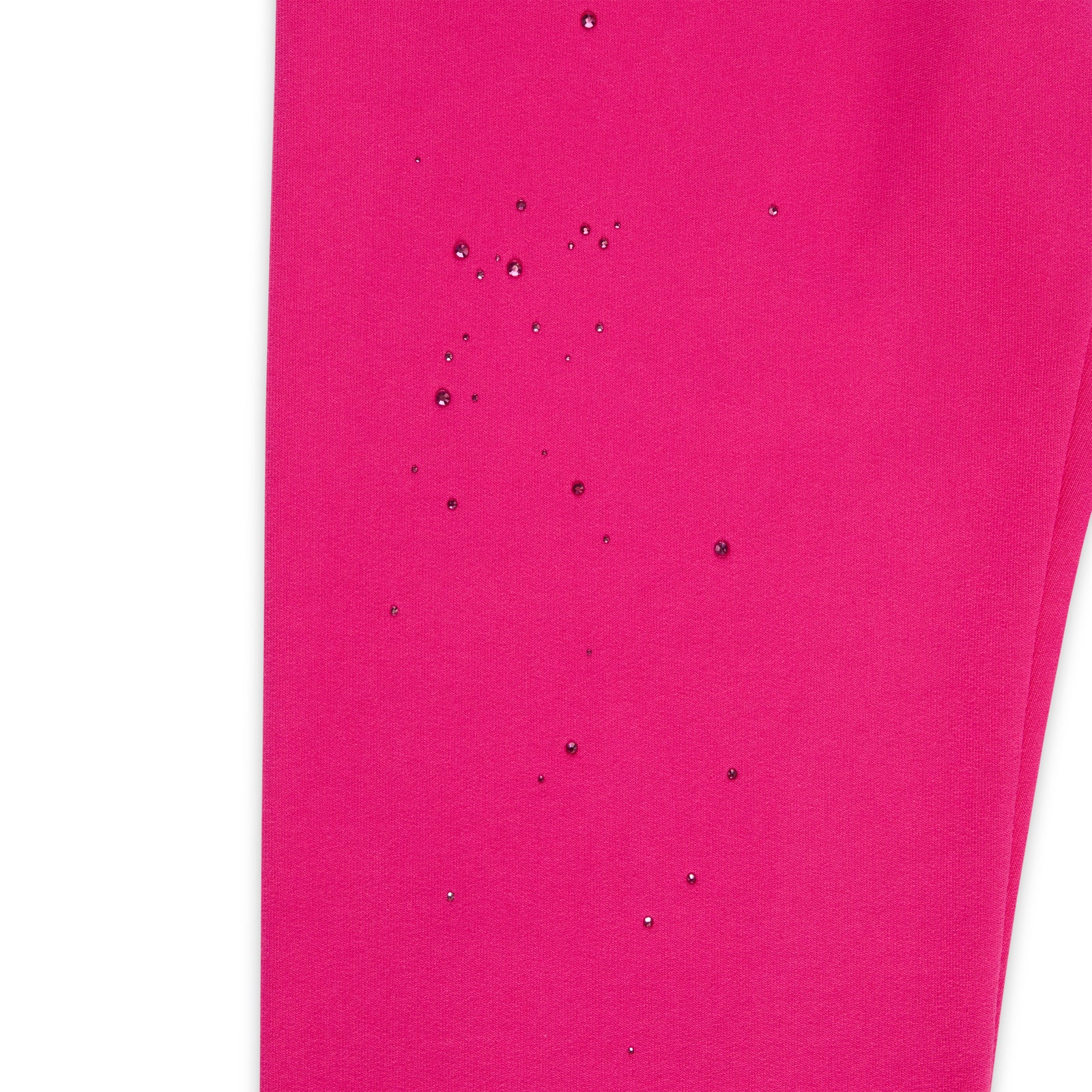 Close-up of vibrant pink cotton fleece sweatpant with scattered rhinestone embellishments.