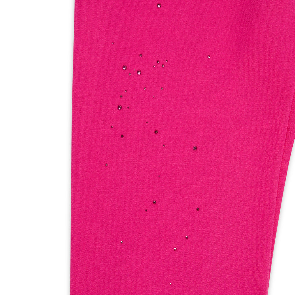 Close-up of vibrant pink cotton fleece sweatpant with scattered rhinestone embellishments.