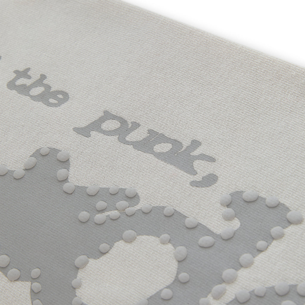 Close-up of light grey cotton fleece sweatpant with puff print "P*NK SP5DER" text and stars.