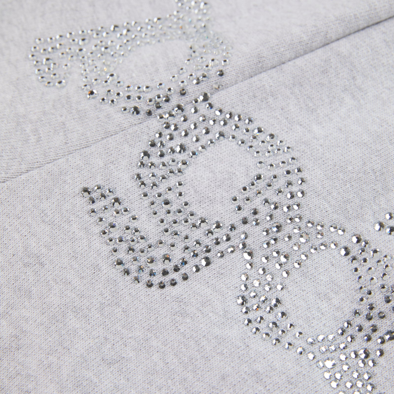 Close-up of gray cotton fleece sweatpants with "SP5DER" text and "5" star design in rhinestones.
