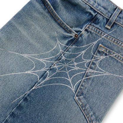 Washed blue denim shorts with a sparkling rhinestone spiderweb design across the back.