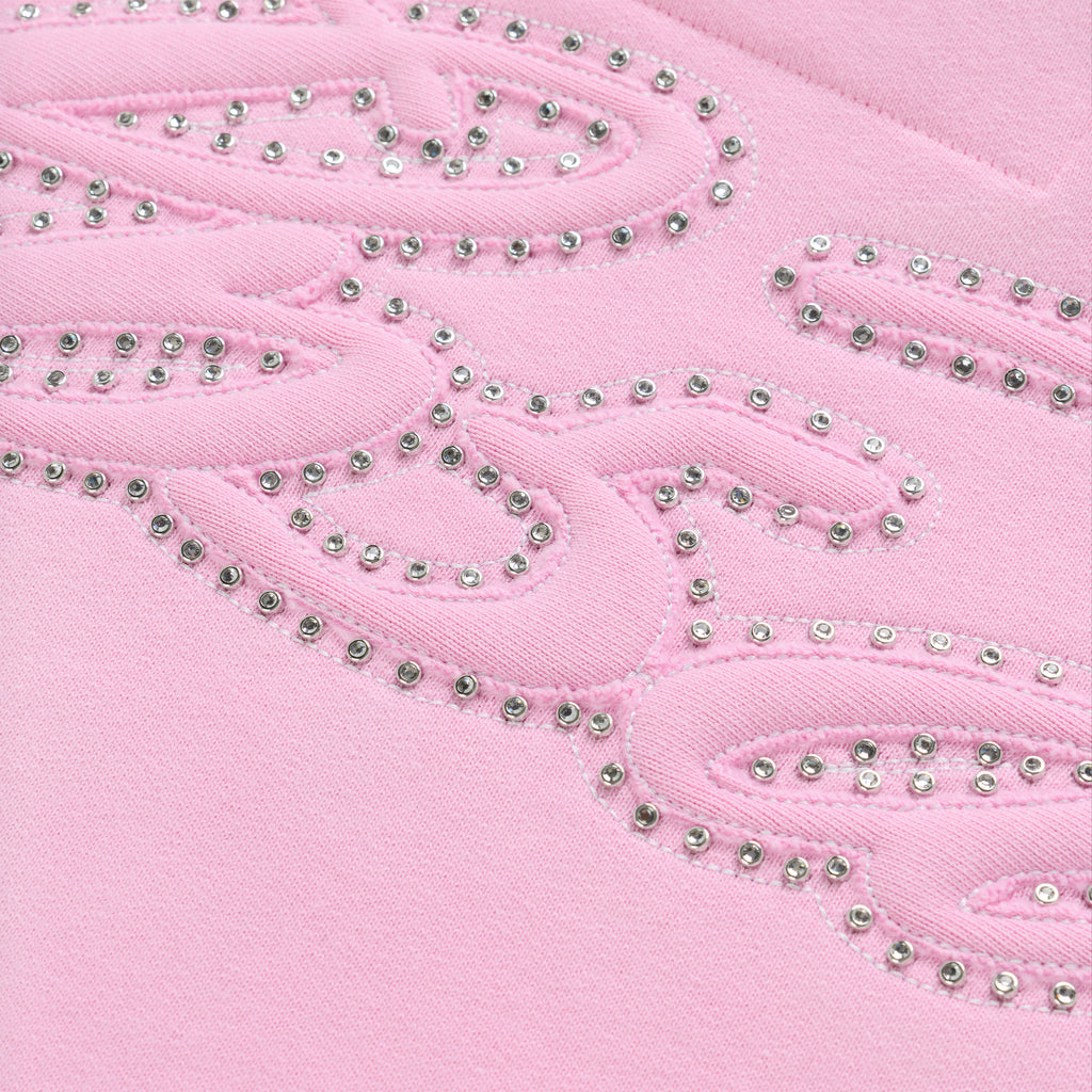 Close-up of a pink cotton fleece hoodie with a rhinestone-lined script design.