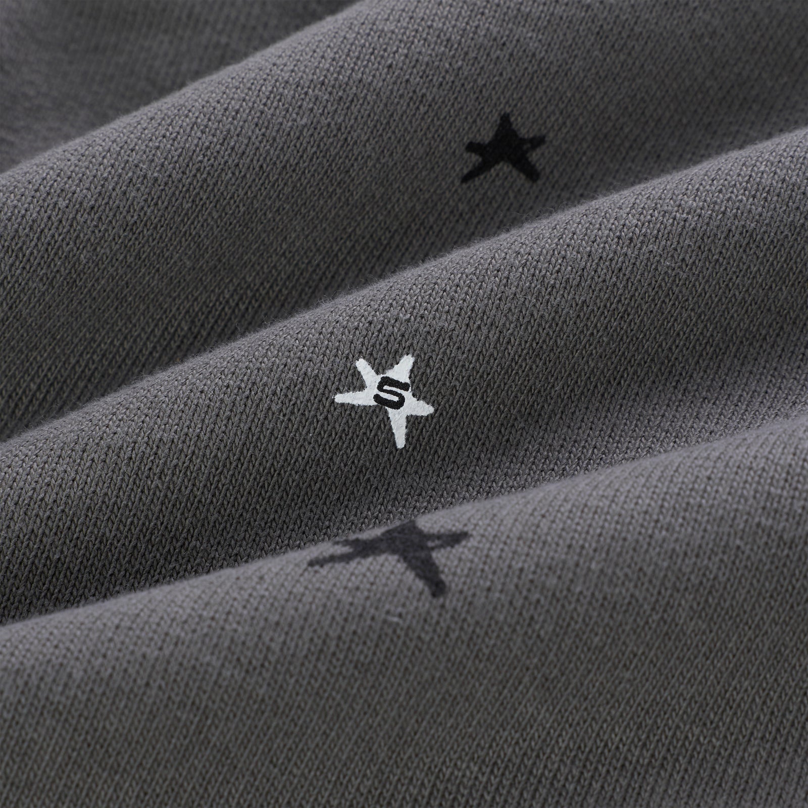 Gray 13oz cotton fleece hoodie with scattered black and white star prints, one white star features an "S".