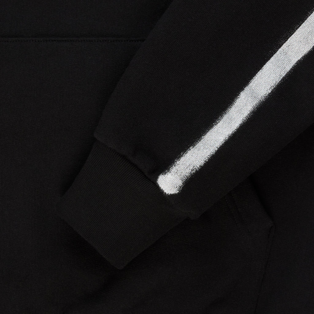 Black cotton fleece hoodie sleeve with white sprayed-effect stripe and ribbed cuff.