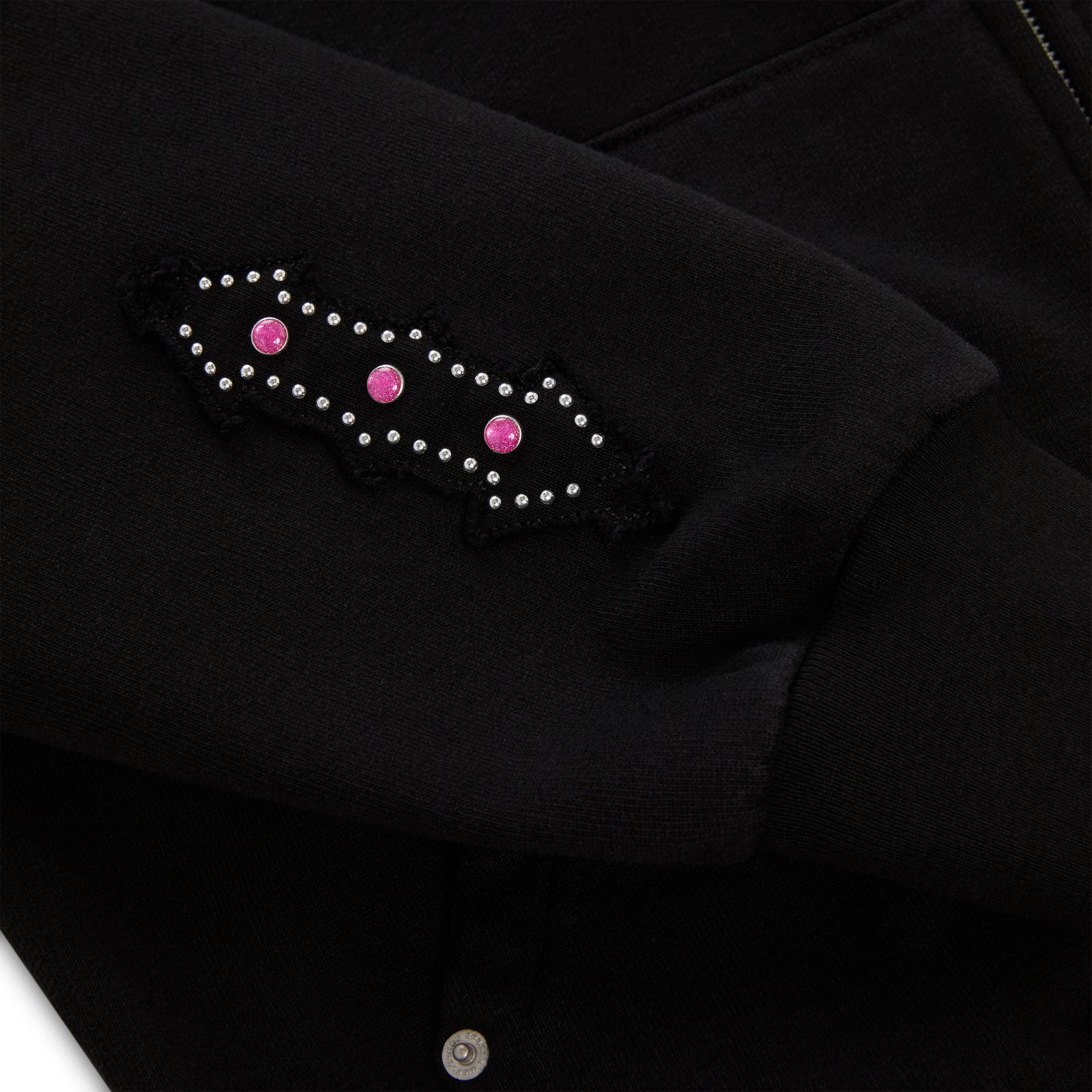 Black 13oz cotton fleece Garibaldi zip-up with patterned sleeve accent and pink stone appliqué.