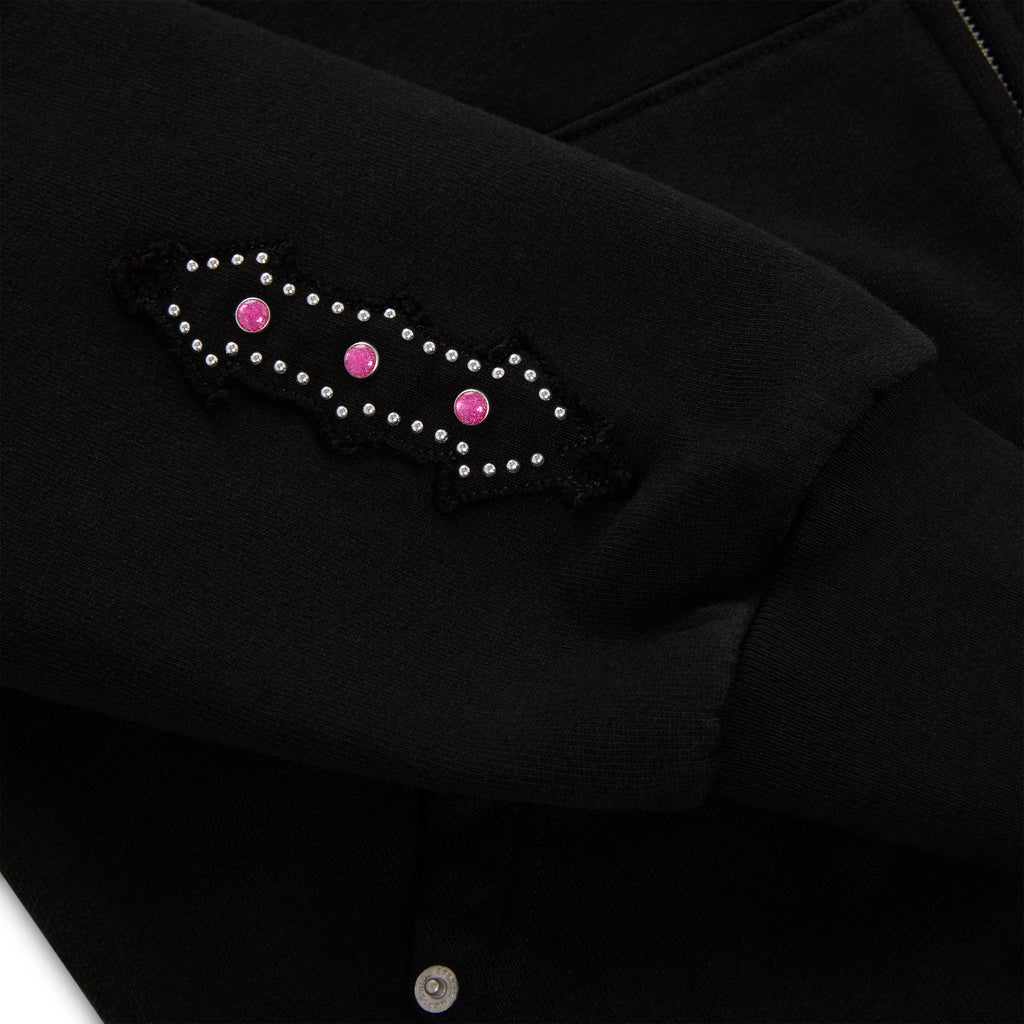 Black 13oz cotton fleece Garibaldi zip-up with patterned sleeve accent and pink stone appliqué.