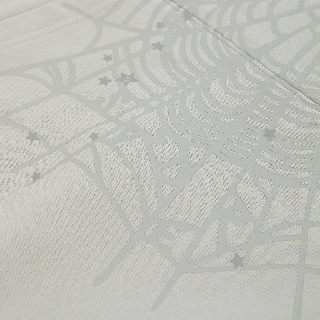Close-up of a light gray cotton fleece hoodie with a subtle spiderweb and scattered star print.