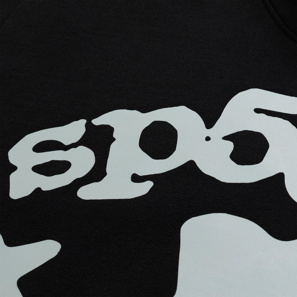 Close-up of a black cotton fleece hoodie with a reflective 'SP5DER' logo.