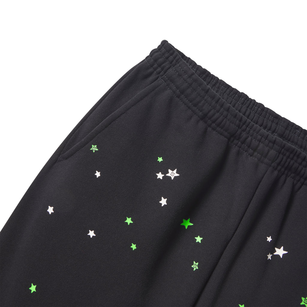 Black cotton fleece sweatpants featuring a scattered white and neon green star graphic print and an elasticized waistband.