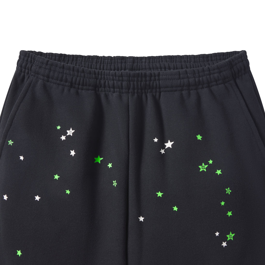 Black cotton fleece sweatpants featuring a scattered green and white star graphic print and an elasticized waistband.