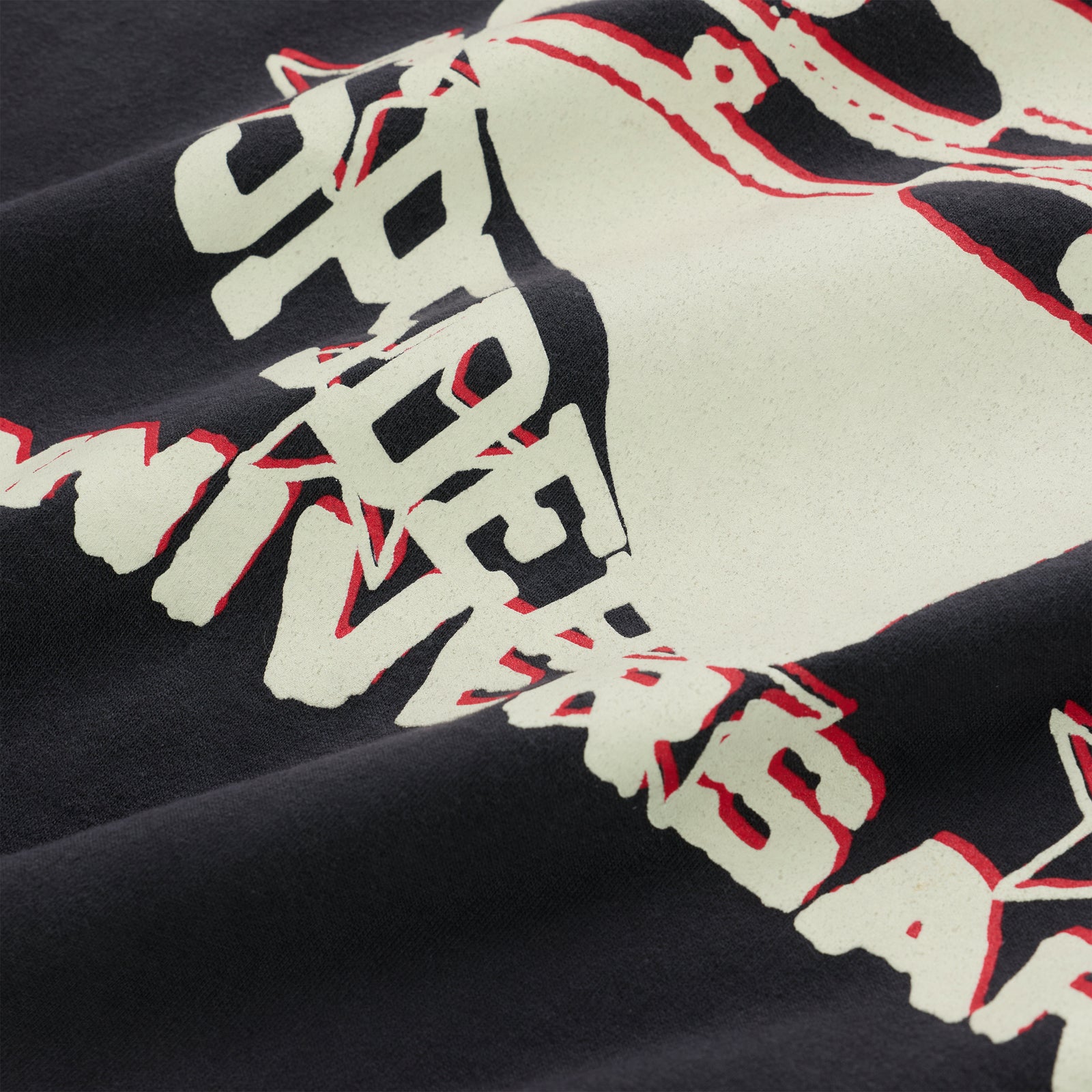 Close-up of a black cotton ANNIVERSARY TEE with a cream and red graphic print.