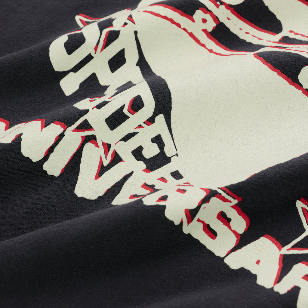 Close-up of a black cotton ANNIVERSARY TEE with a cream and red graphic print.