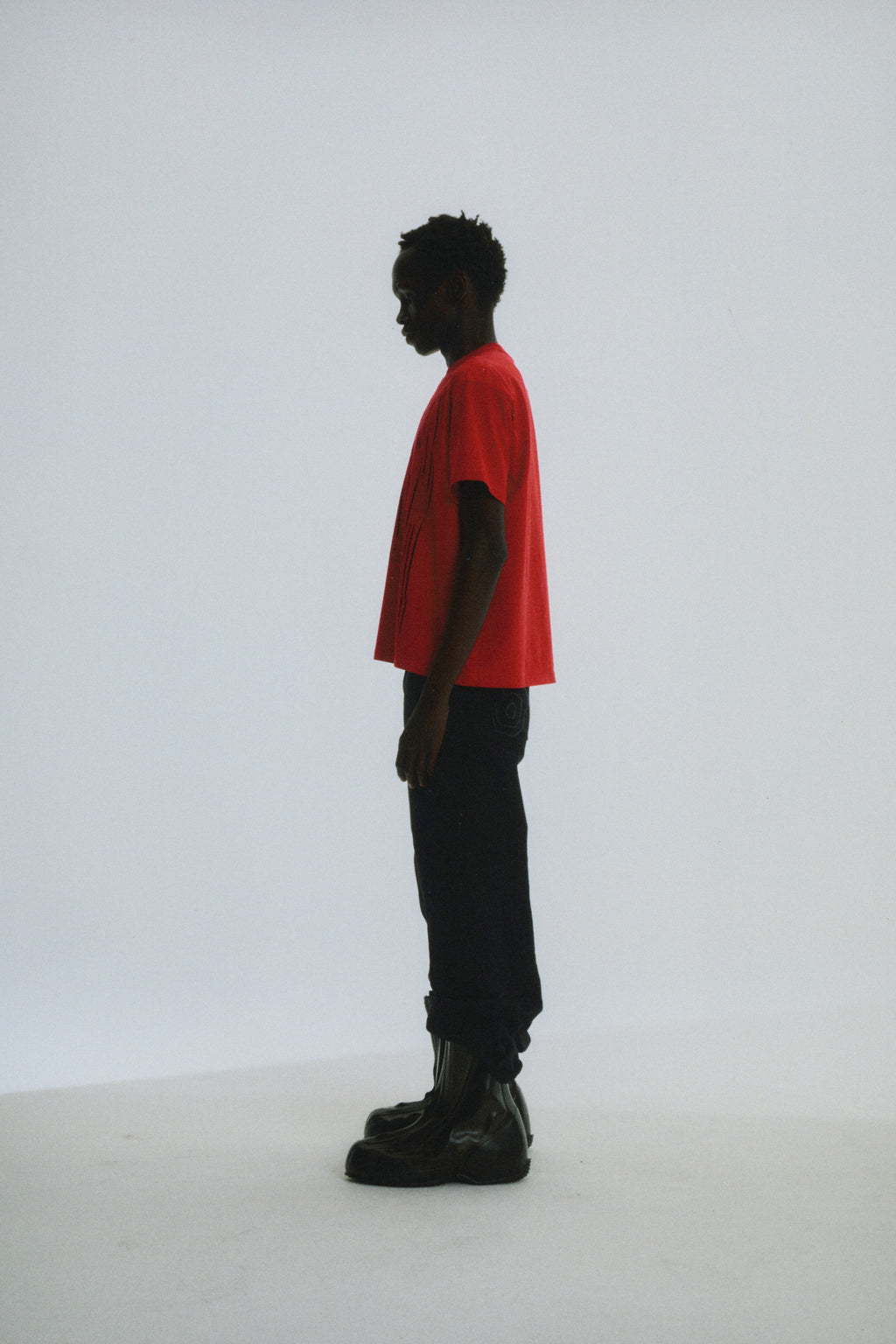 Red cotton DIFFUSED COLLEGIATE TEE with graphic print, worn by a person in profile.