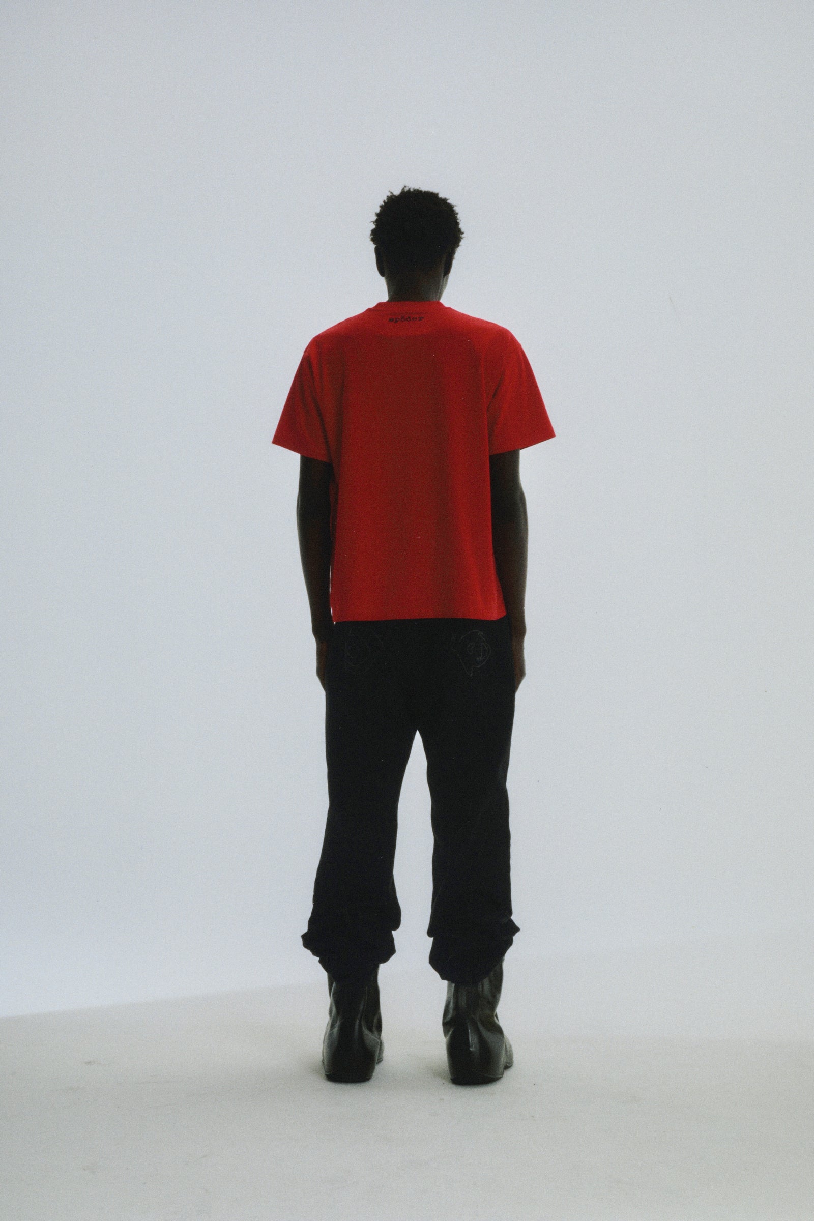 Red cotton tee with 'SP5DER' logo on back neck, worn by a person facing away.