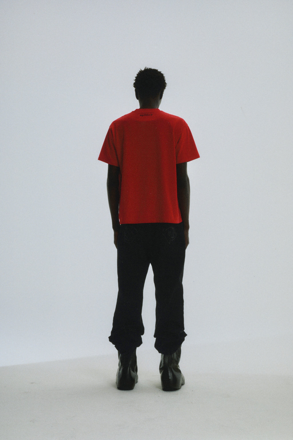 Red cotton tee with 'SP5DER' logo on back neck, worn by a person facing away.