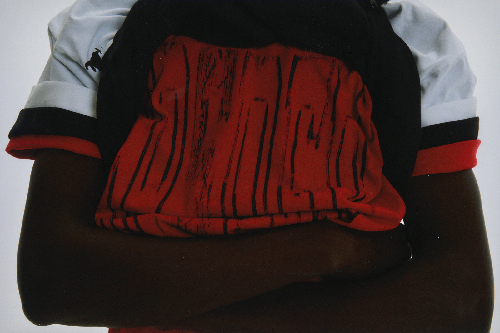 Black and red cotton collegiate tee with distressed graphic print on front, white sleeves.
