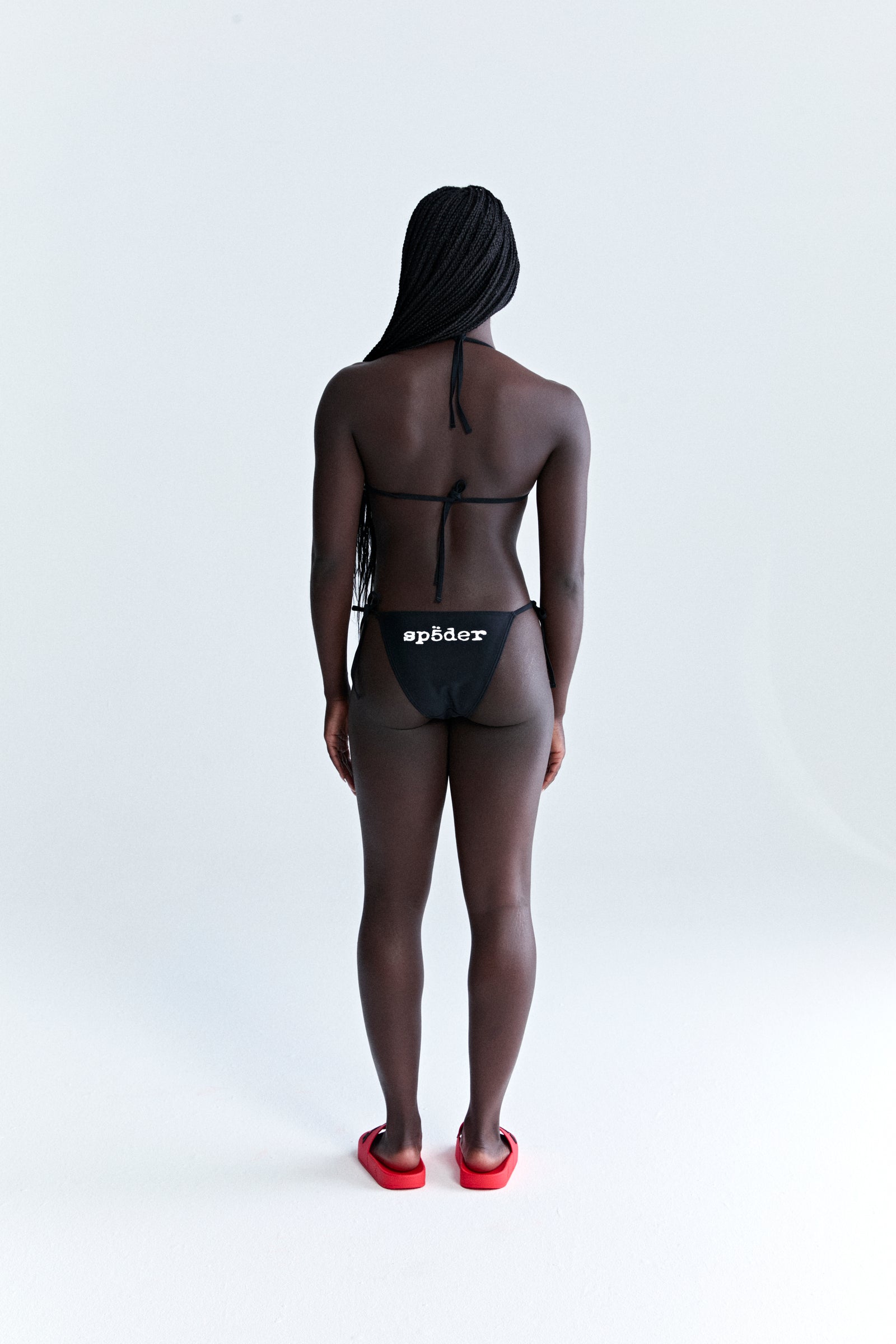 Black stretch nylon jersey ARAIGNÉE bikini with rope ties, crest graphic on top, and "spöder" logo on bottom.