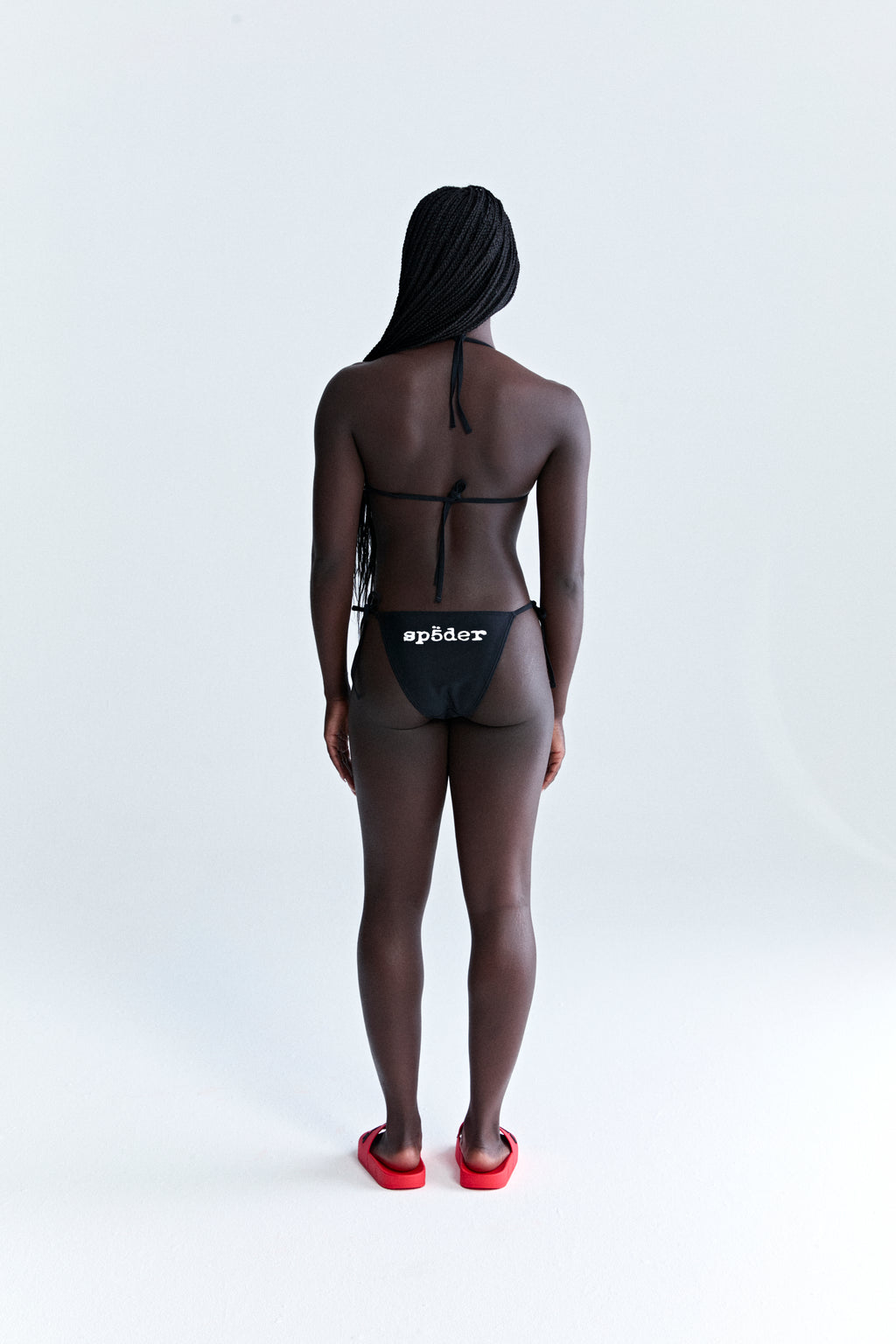 Black stretch nylon jersey ARAIGNÉE bikini with rope ties, crest graphic on top, and "spöder" logo on bottom.