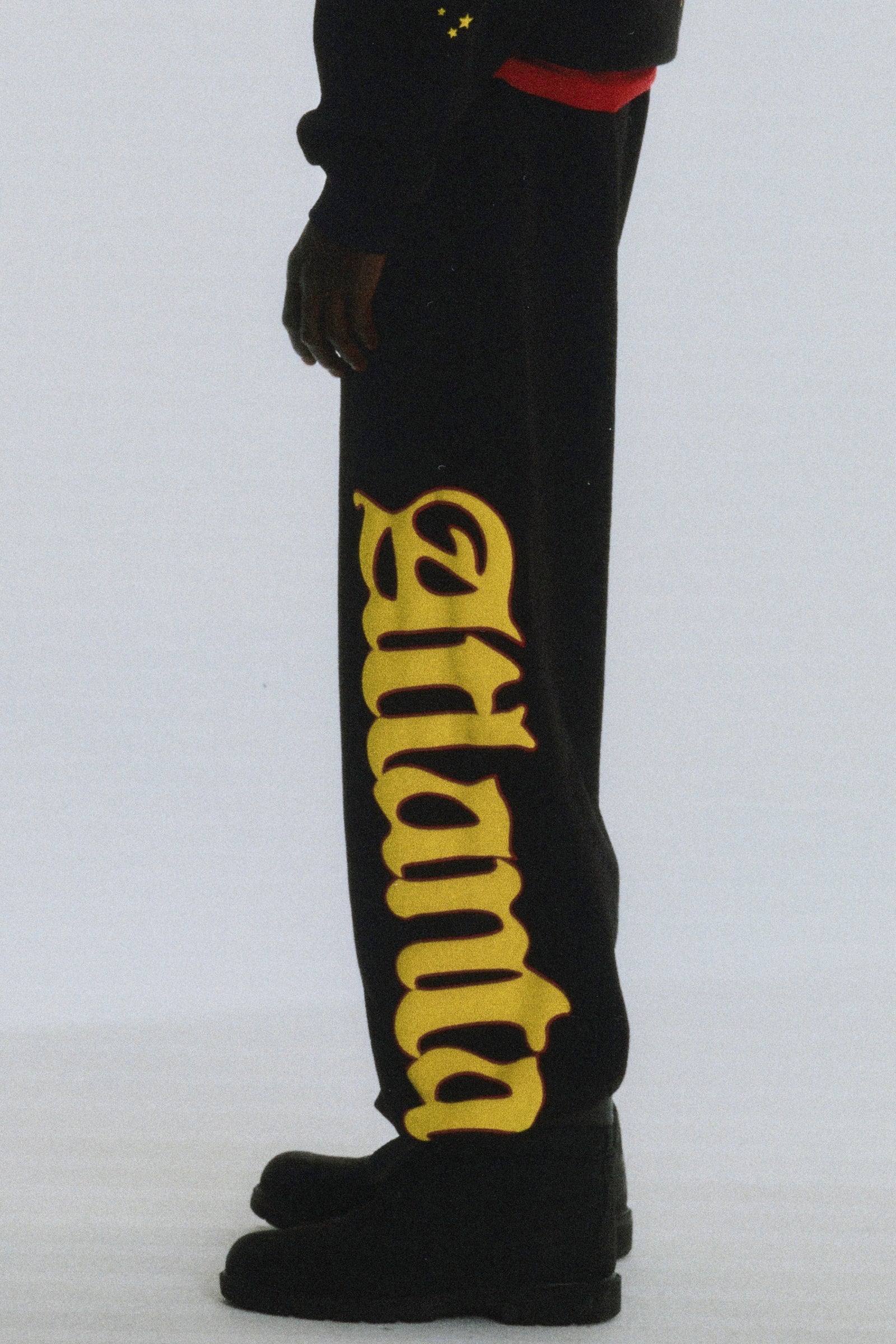 Black cotton fleece sweatpants with yellow "Atlanta" script and scattered stars on the left leg.
