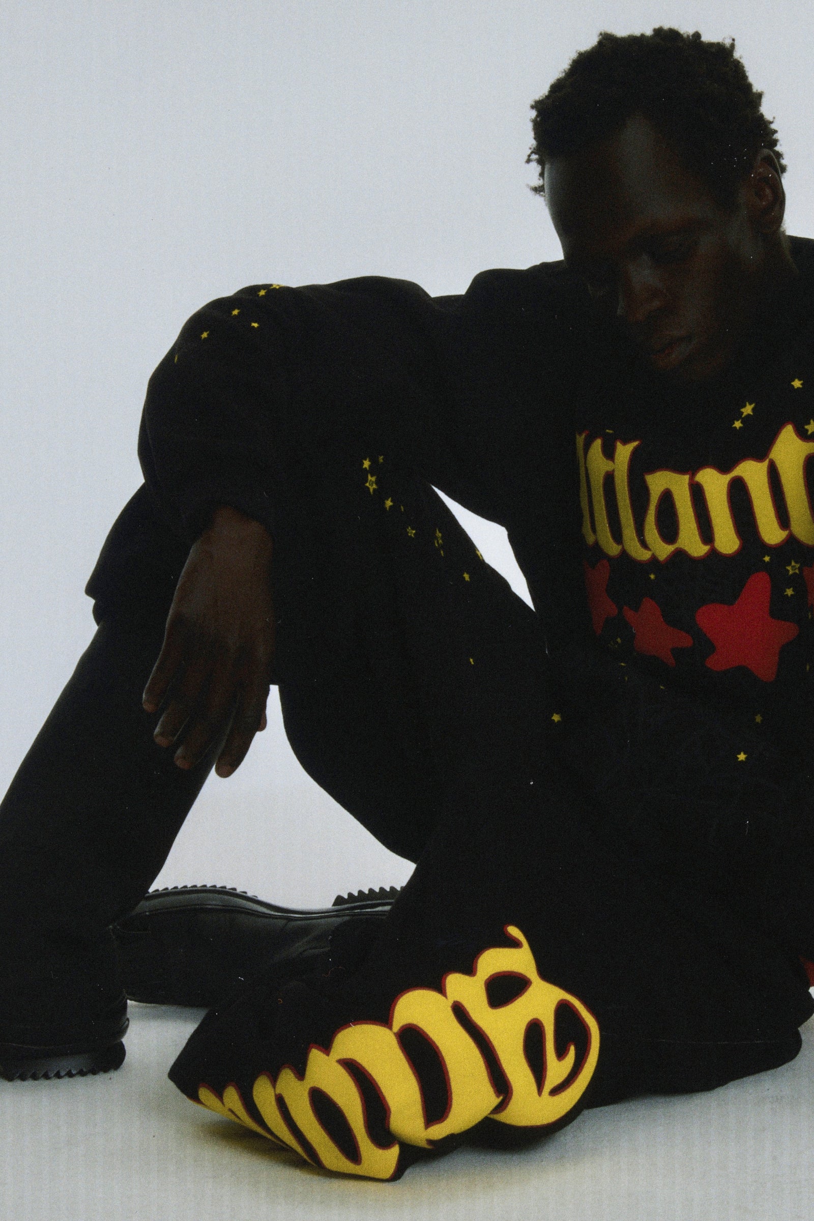 Black cotton fleece Atlanta sweatpants with yellow script text and scattered star print.