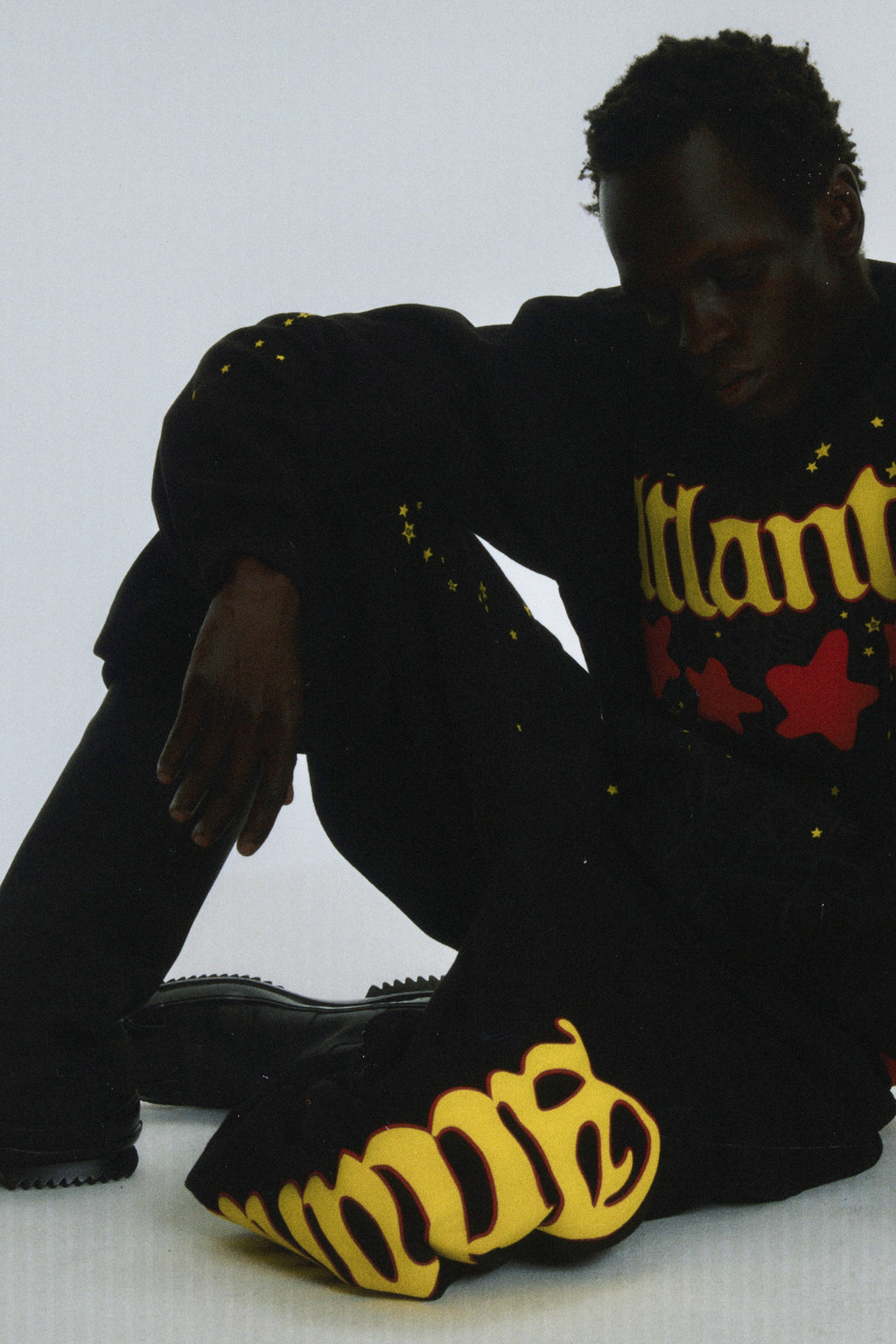 Black cotton fleece Atlanta sweatpants with yellow script text and scattered star print.