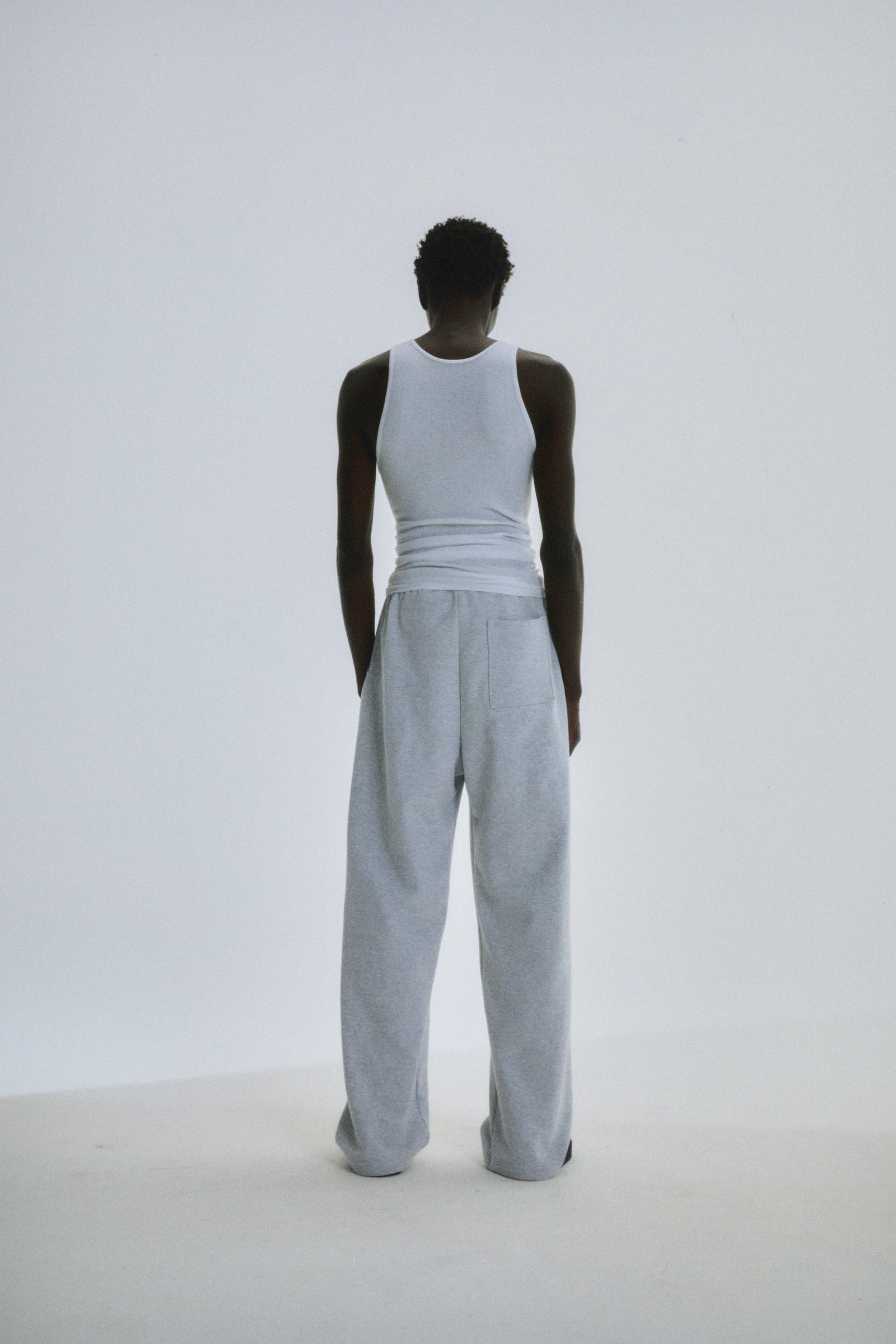 Person from behind wearing light grey wide-leg cotton fleece sweatpants with elastic waistband.