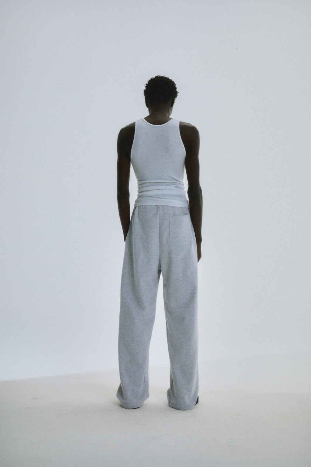 Person from behind wearing light grey wide-leg cotton fleece sweatpants with elastic waistband.