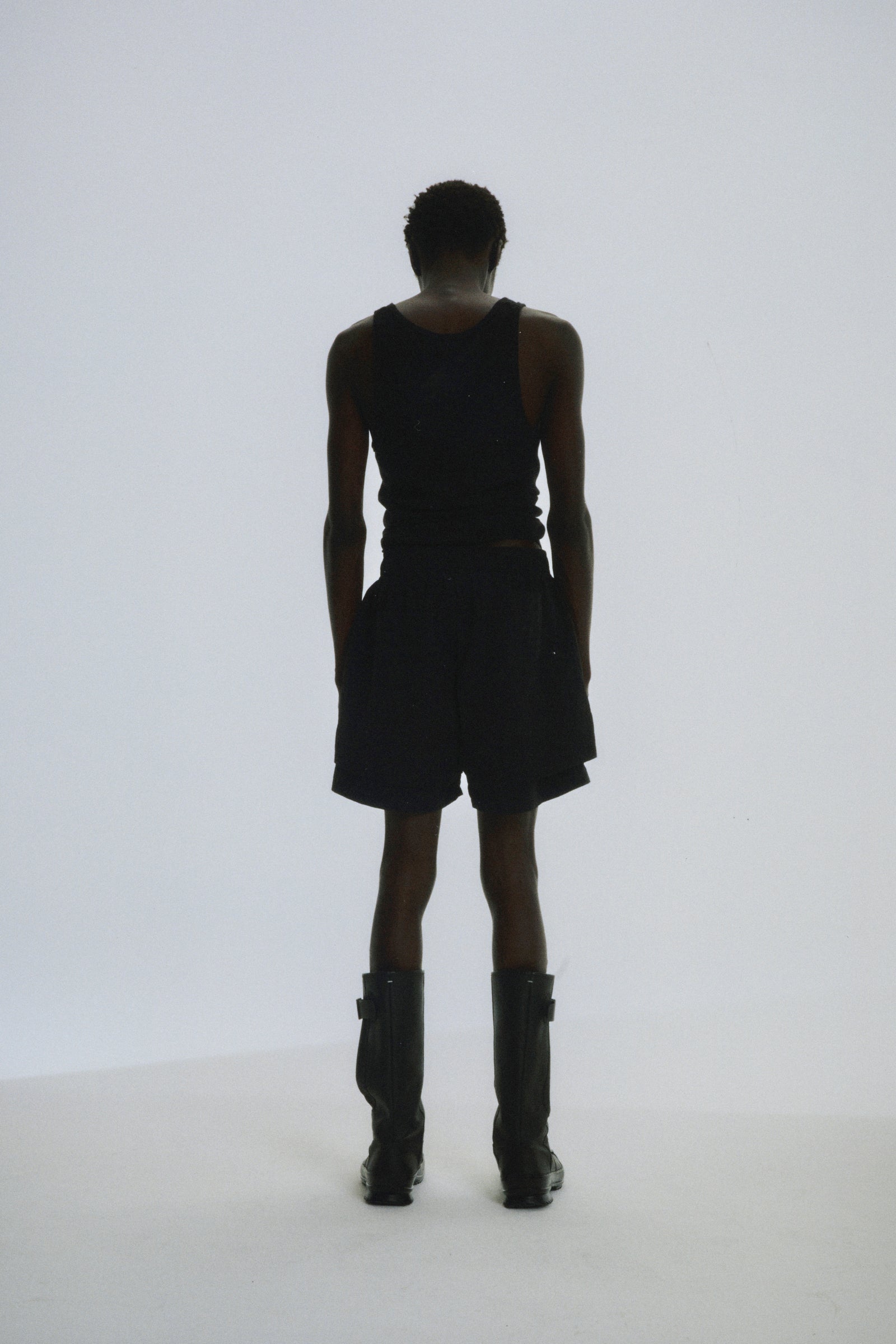 Man from behind wearing black Beluga Double Layer Shorts and a black tank top.