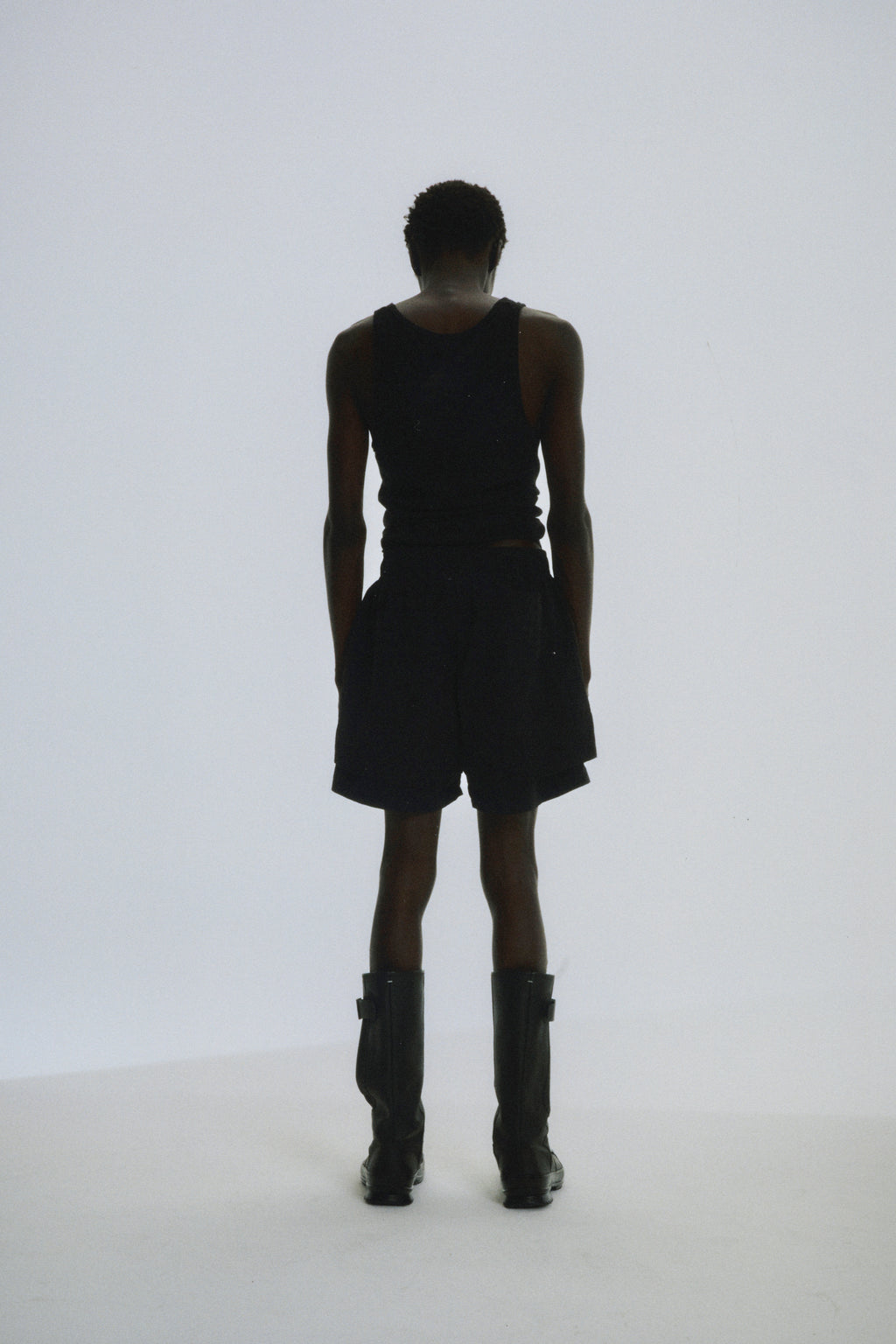 Man from behind wearing black Beluga Double Layer Shorts and a black tank top.