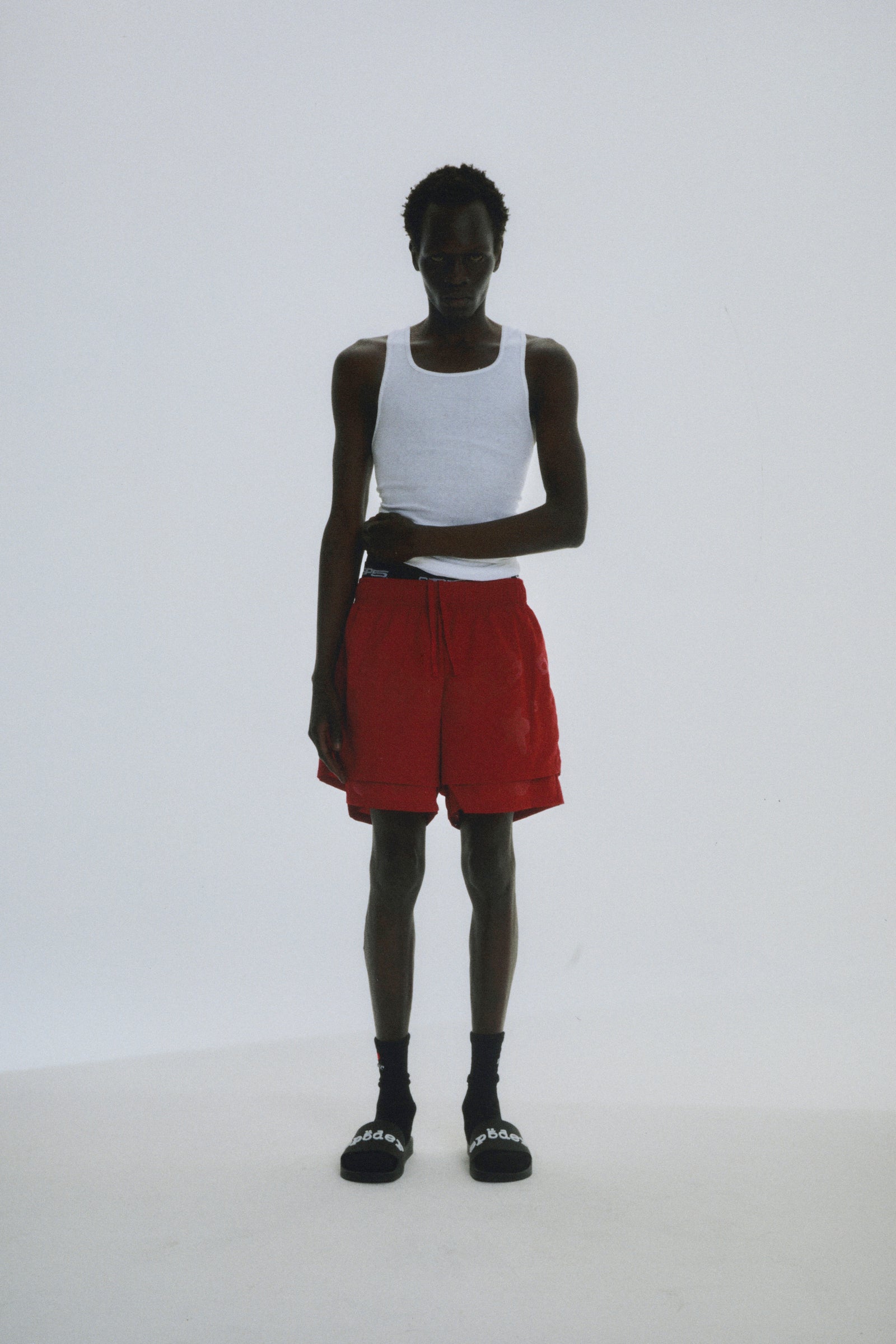 Man in red Beluga Double Layer Shorts, 4oz water repellent nylon, with high-low design and puff print.