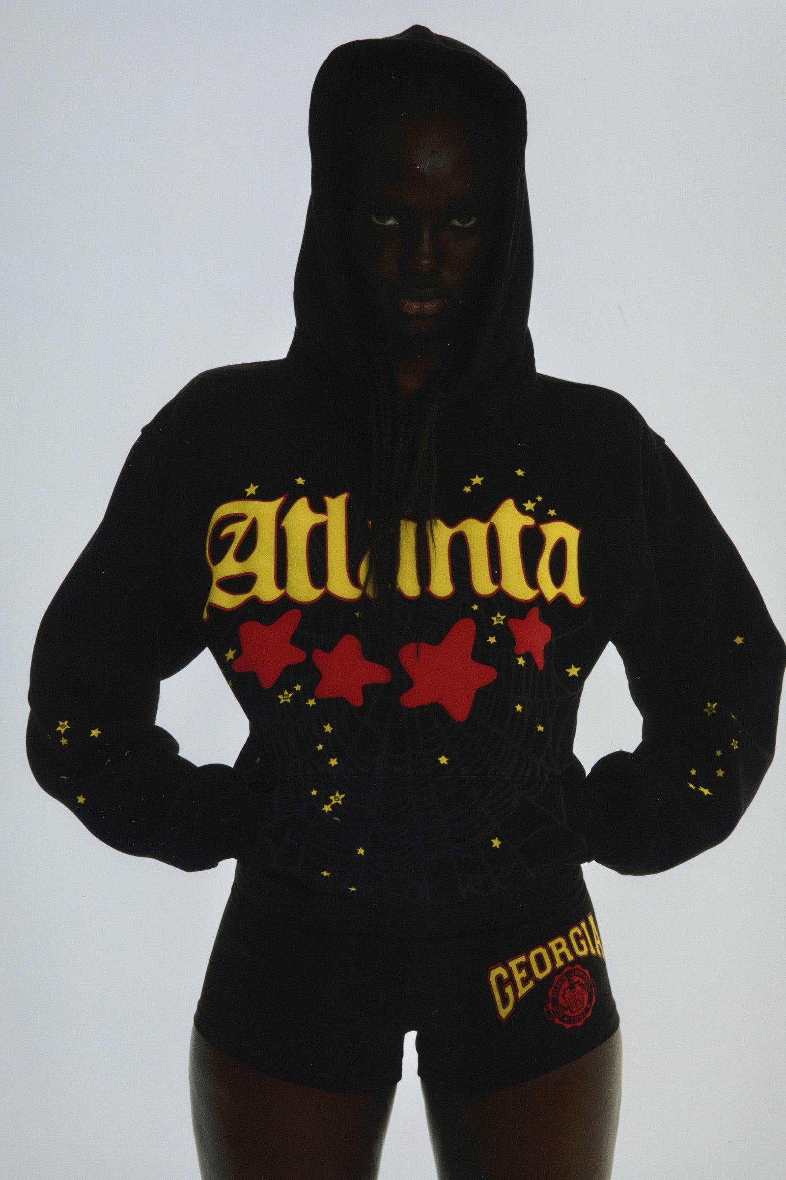 Black cotton fleece Atlanta hoodie with yellow script text, red stars, and web print.