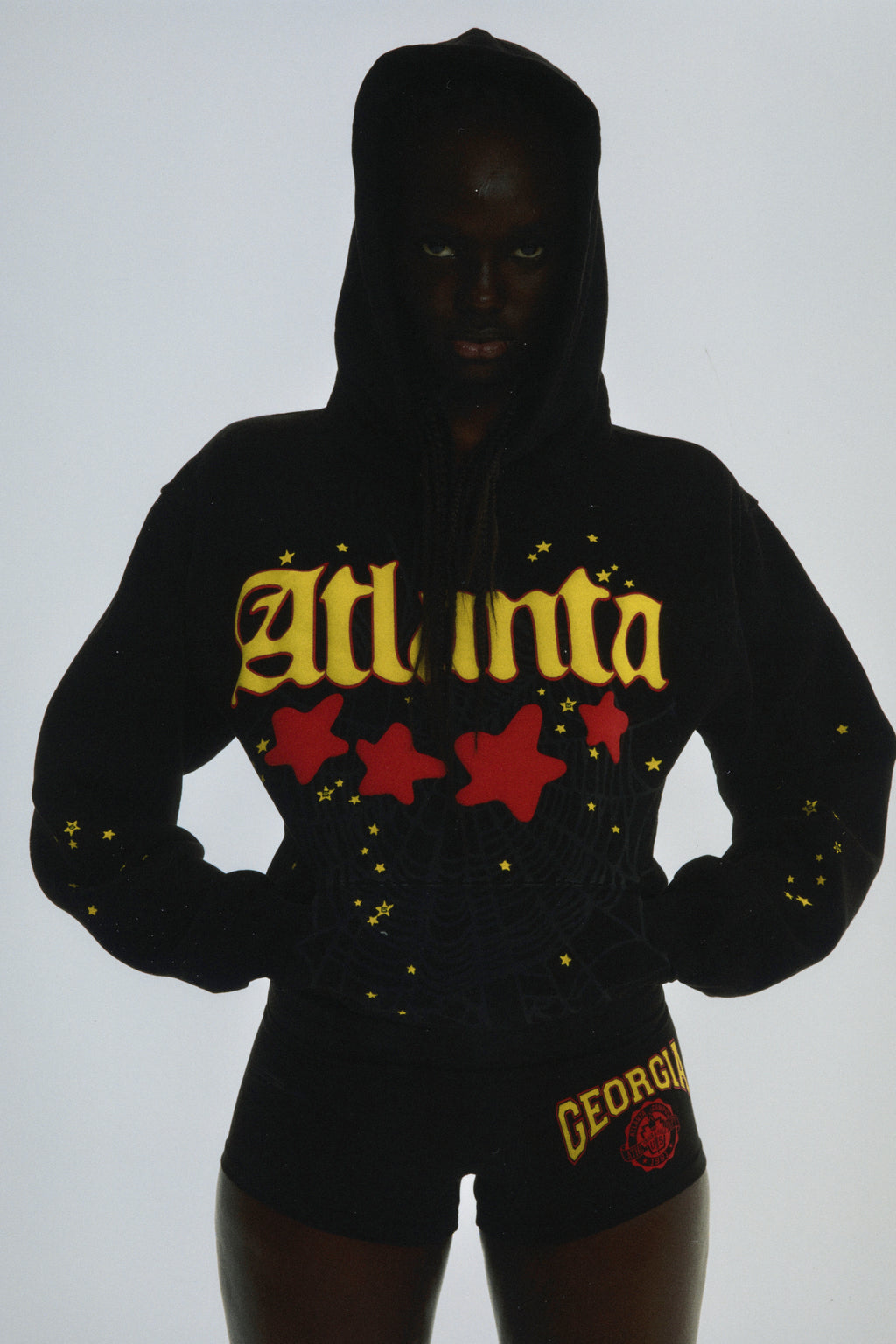 Black cotton fleece Atlanta hoodie with yellow script text, red stars, and web print.