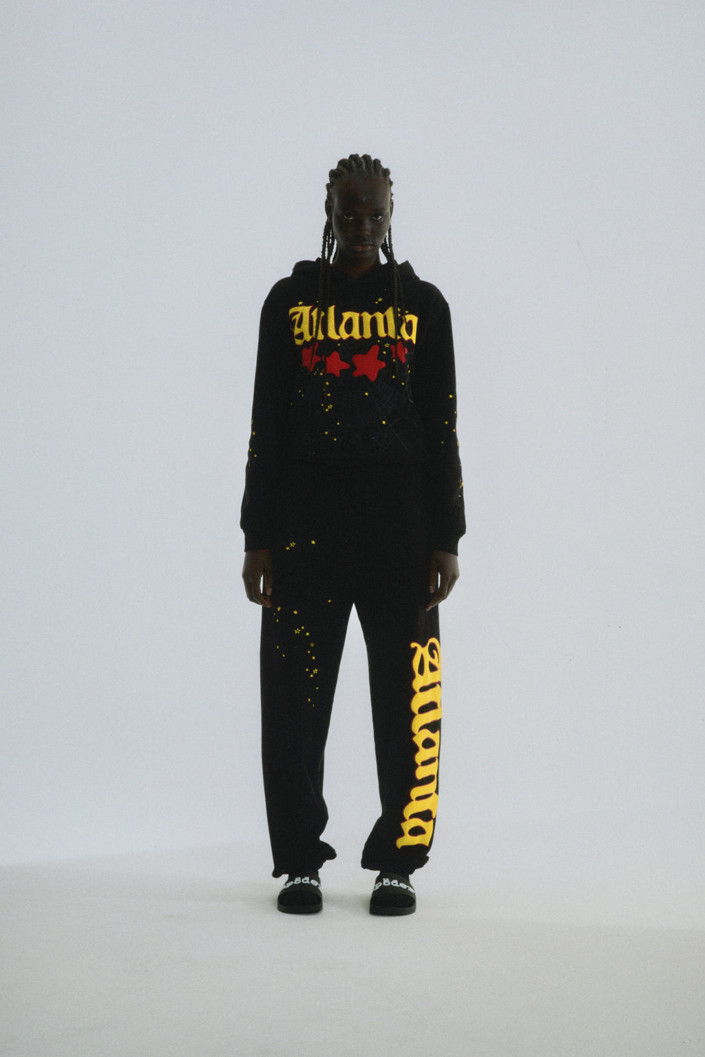 Black 100% cotton fleece Atlanta hoodie and sweatpants with yellow puff print script and scattered stars.