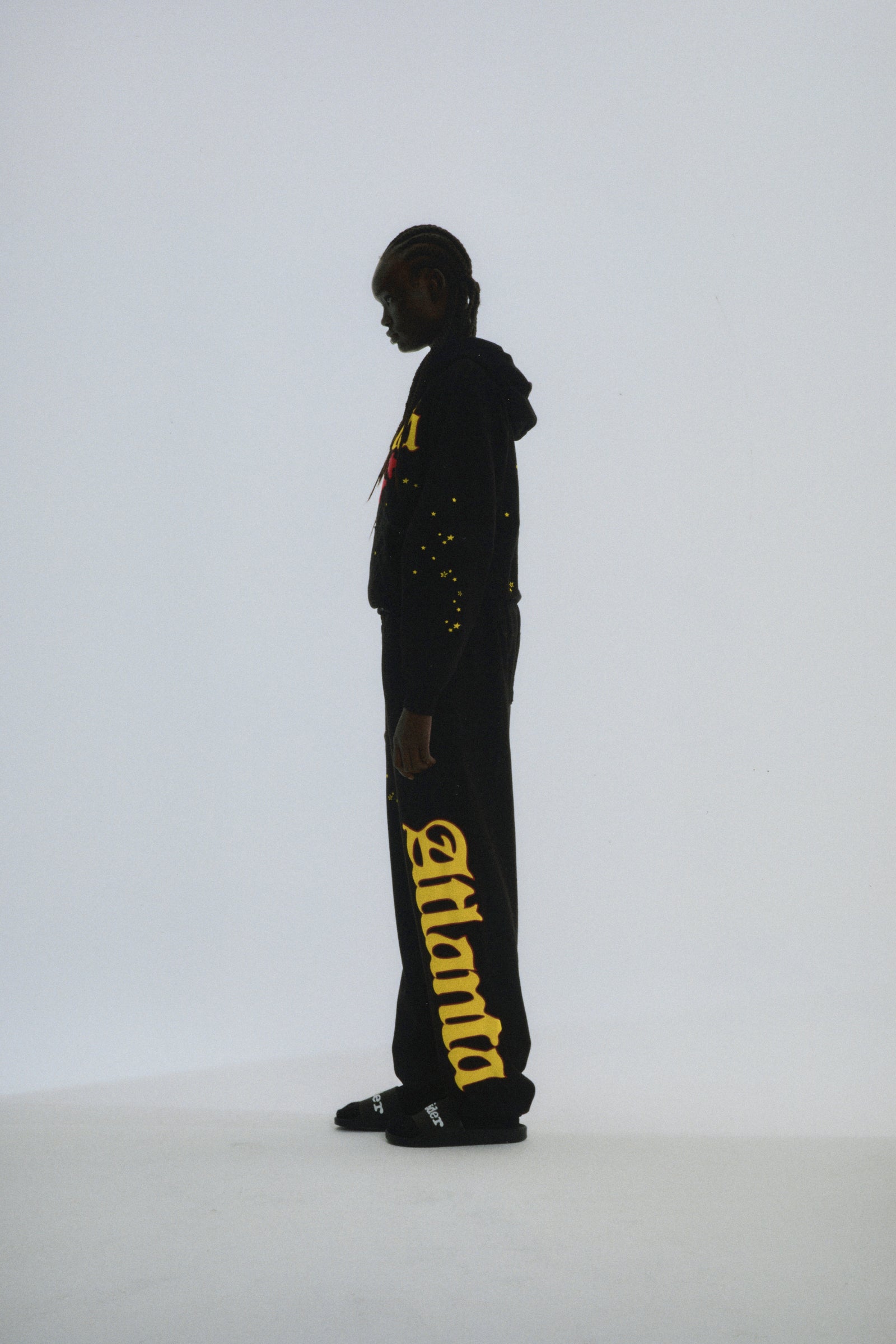 Black Atlanta hoodie and sweatpants with yellow puff print script, web, and scattered star designs.