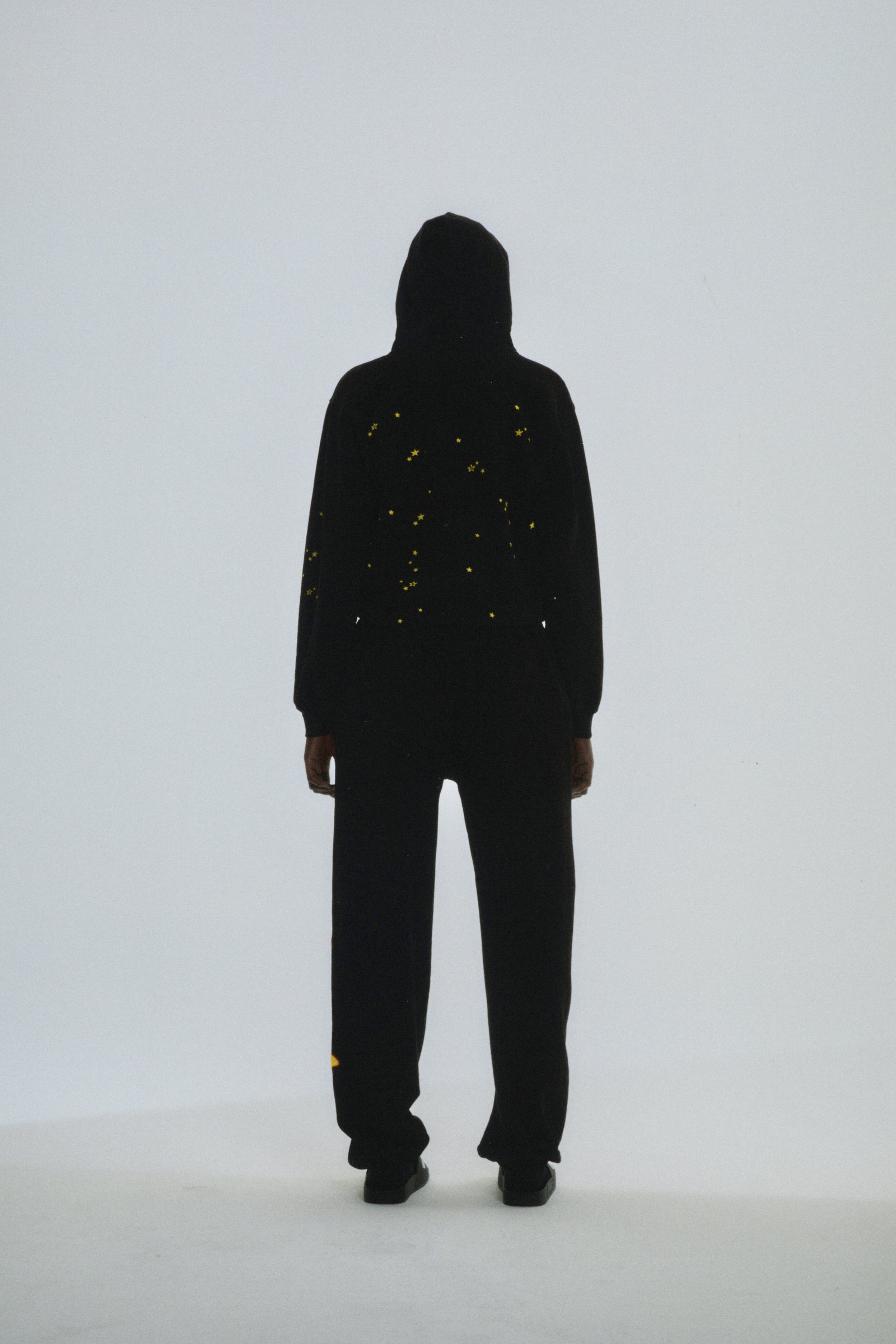 Black cotton fleece Atlanta Hoodie with scattered yellow star print, seen from the back.