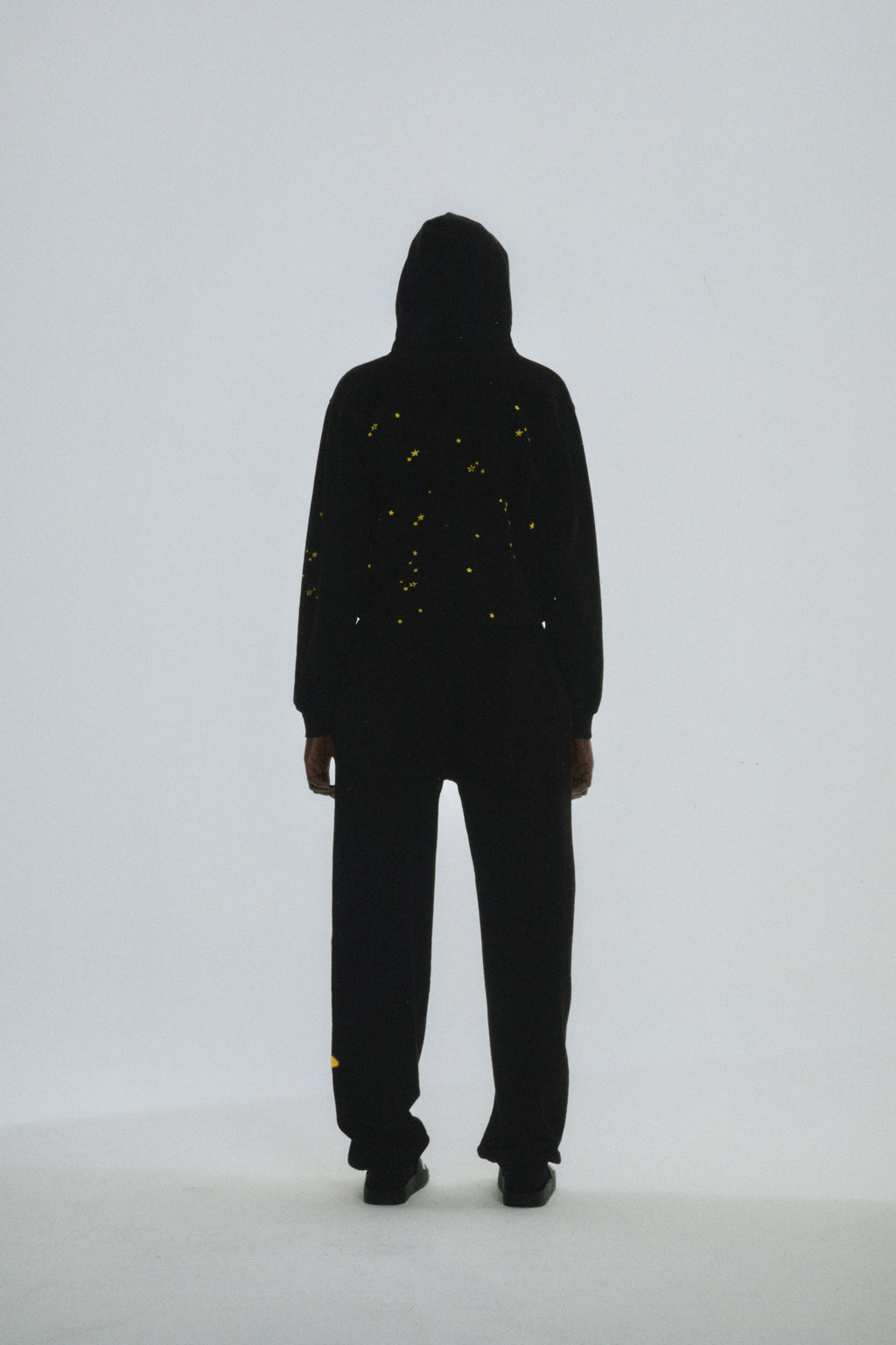 Black cotton fleece Atlanta Hoodie with scattered yellow star print, seen from the back.